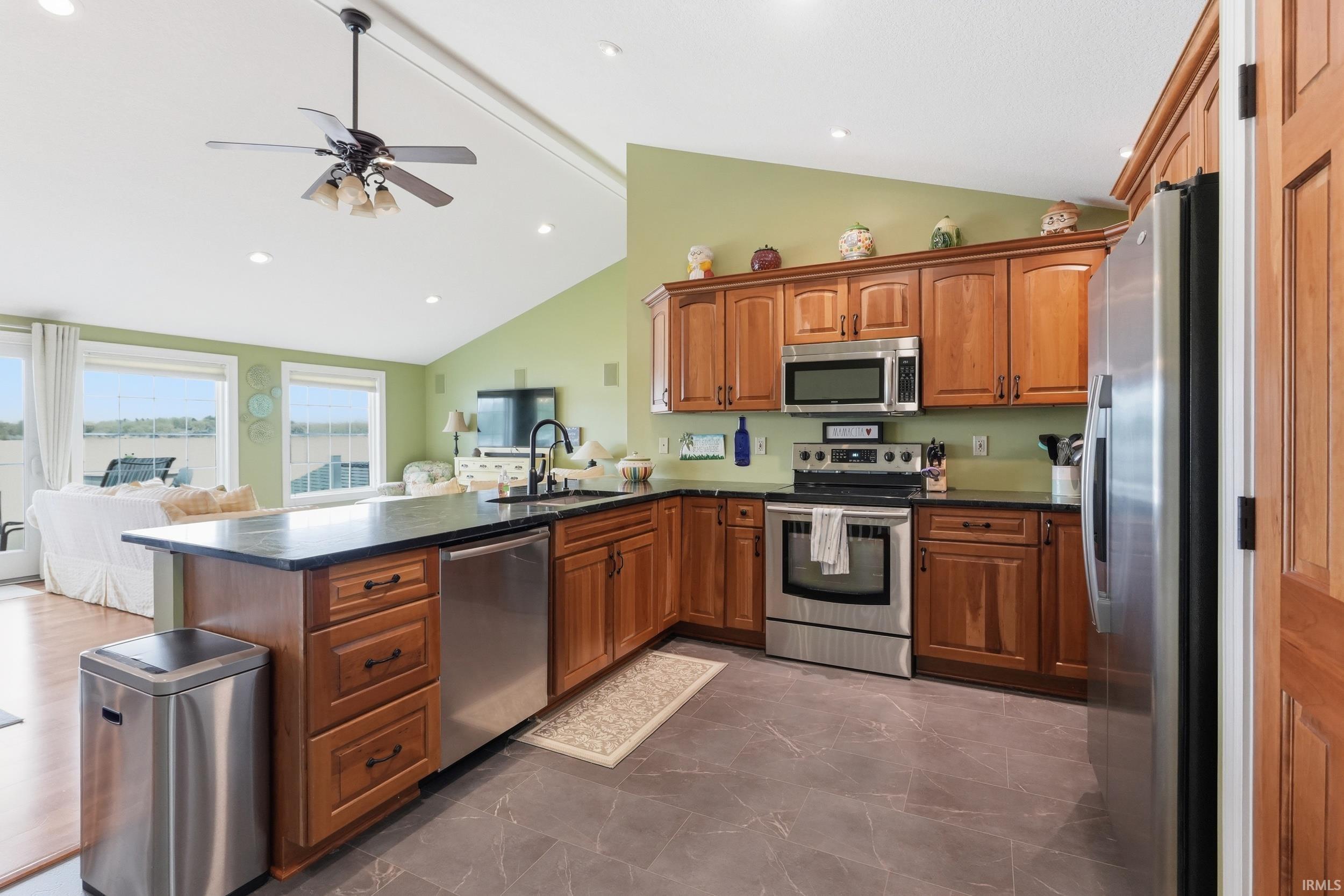 Image 2: Kitchen featuring wood cabinetry with dark hardware, dark countertops, and stainless steel appliances, Kitchen