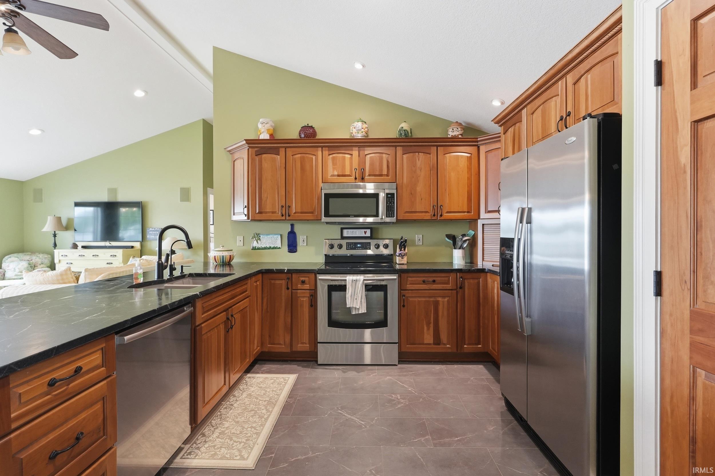 Image 3: Kitchen featuring wood cabinetry, stainless steel appliances, dark countertops, and a black gooseneck faucet, Kitchen