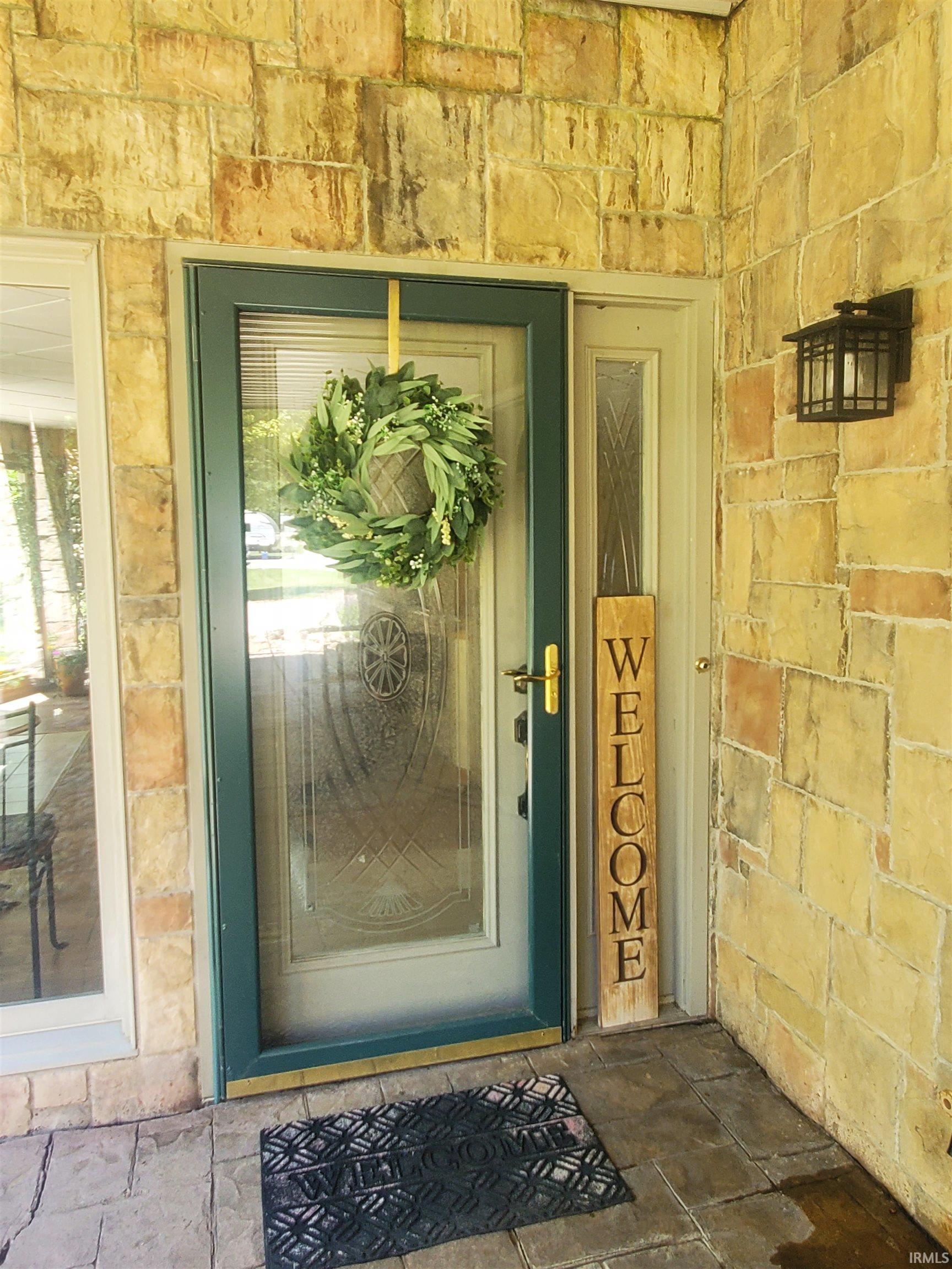 Image 1: Stone exterior featuring a glass-paneled entry door, adjacent sidelight, and an exterior wall lantern, Entry Image 1: Stone exterior featuring a glass-paneled entry door, adjacent sidelight, and an exterior wall lantern, Entry