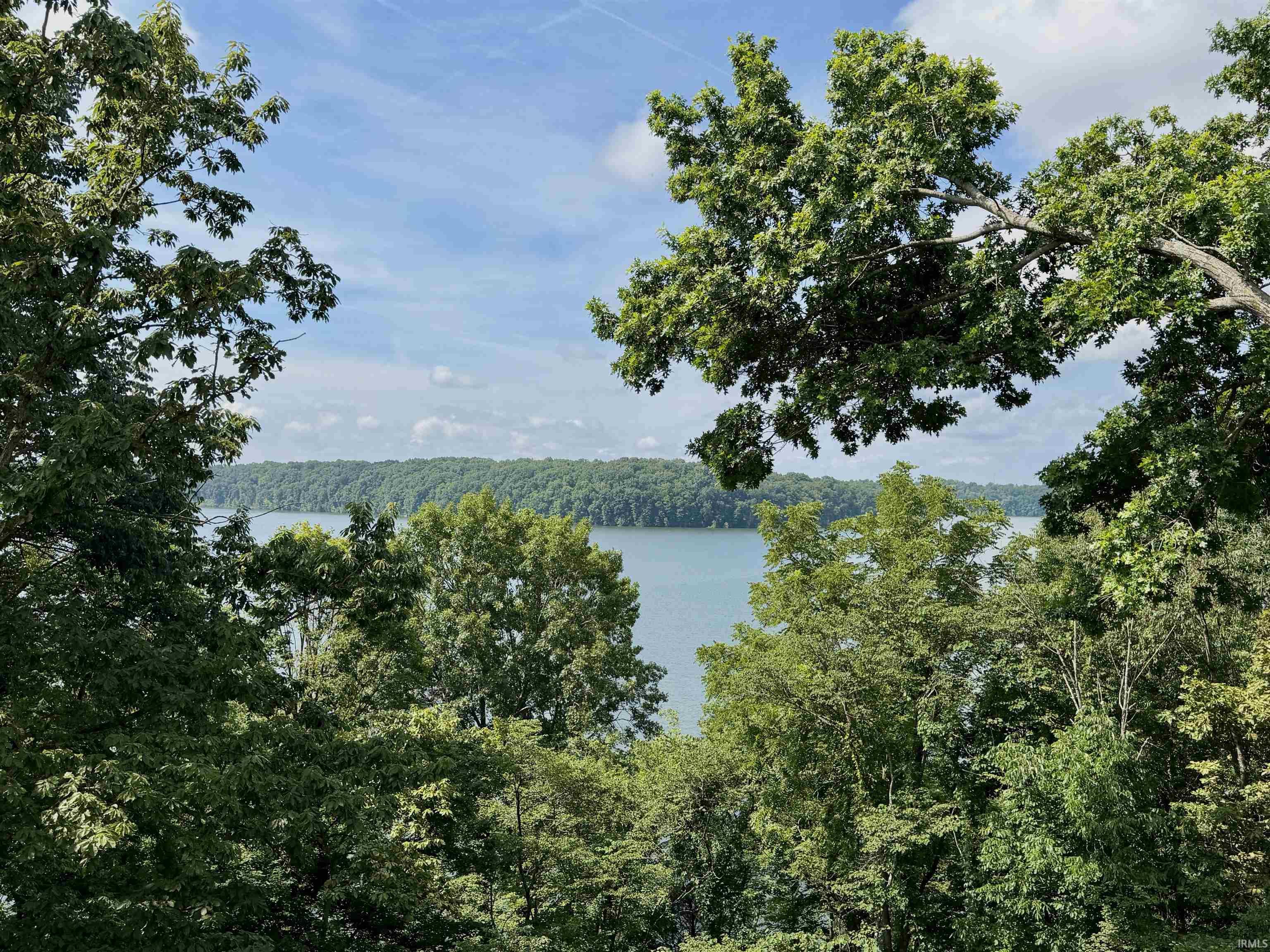 Image 1: Expansive water vista framed by mature trees and lush foliage under a clear sky, View Image 1: Expansive water vista framed by mature trees and lush foliage under a clear sky, View