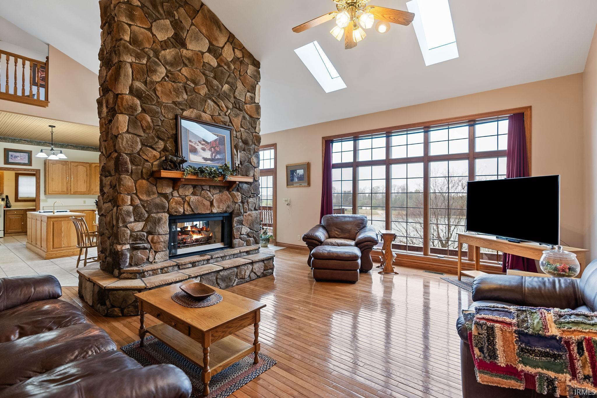 Image 3: Living room featuring vaulted ceiling, light wood-style floors, a ceiling fan, and a fireplace, Living Room Image 3: Living room featuring vaulted ceiling, light wood-style floors, a ceiling fan, and a fireplace, Living Room