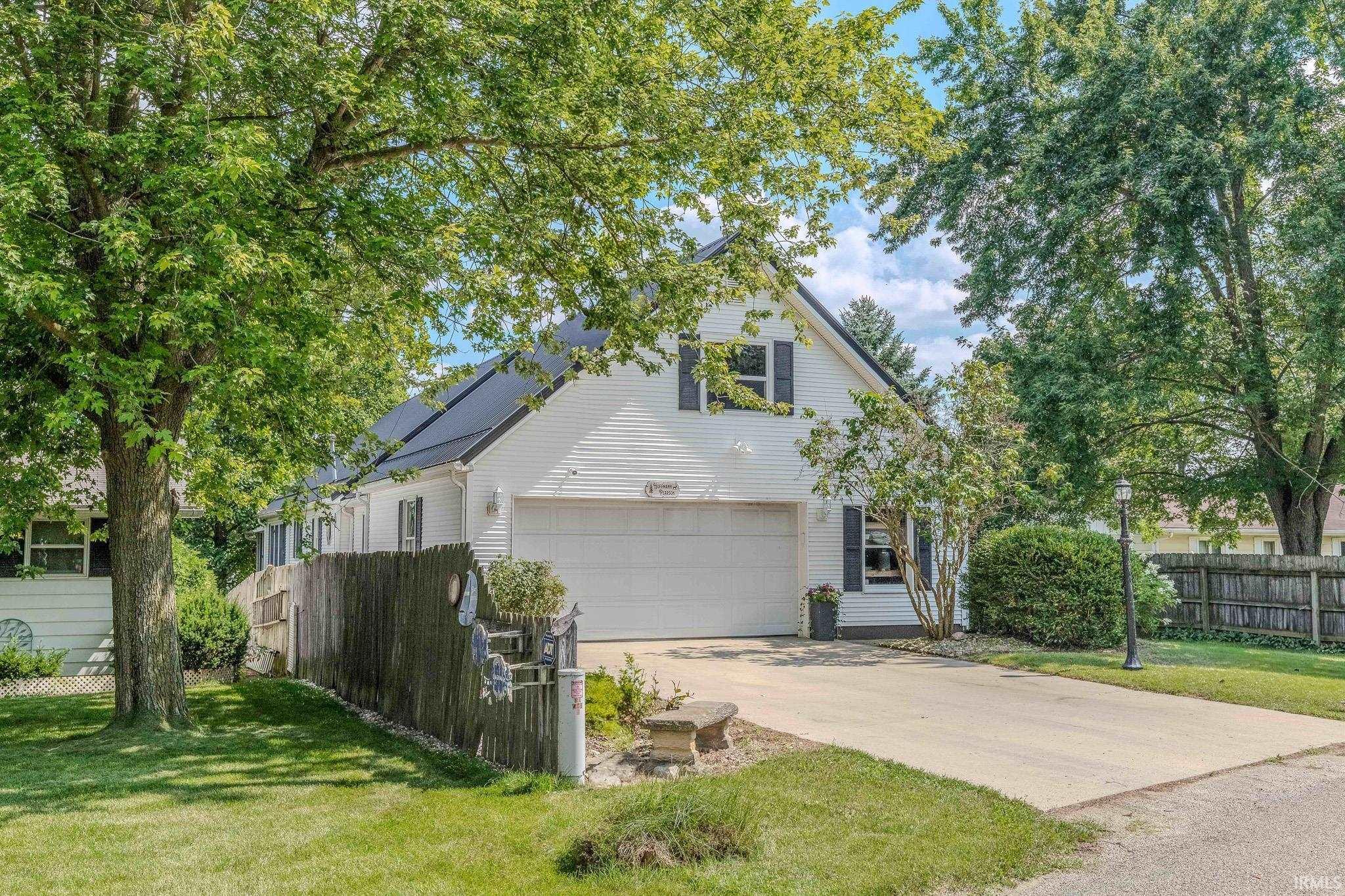 Image 1: White-sided residence featuring a two-car garage, black window shutters, and a dark shingle roof, Front Of Structure