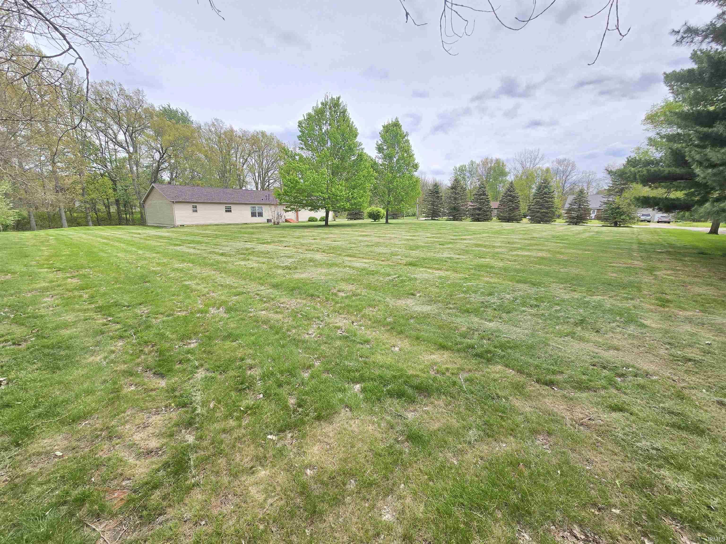 Image 2: Expansive open lawn area with partial tree-lined perimeter, Yard