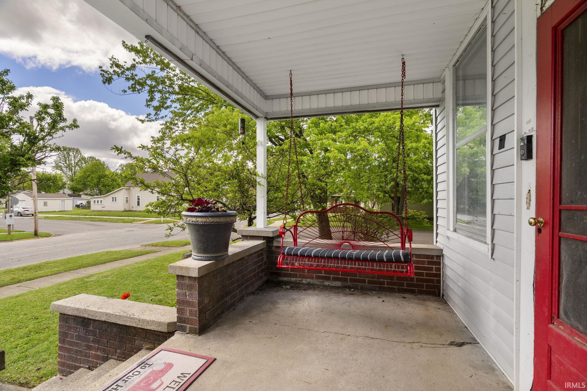 Image 3: Covered front porch with brick half-walls, concrete flooring, and a white paneled ceiling, Patio