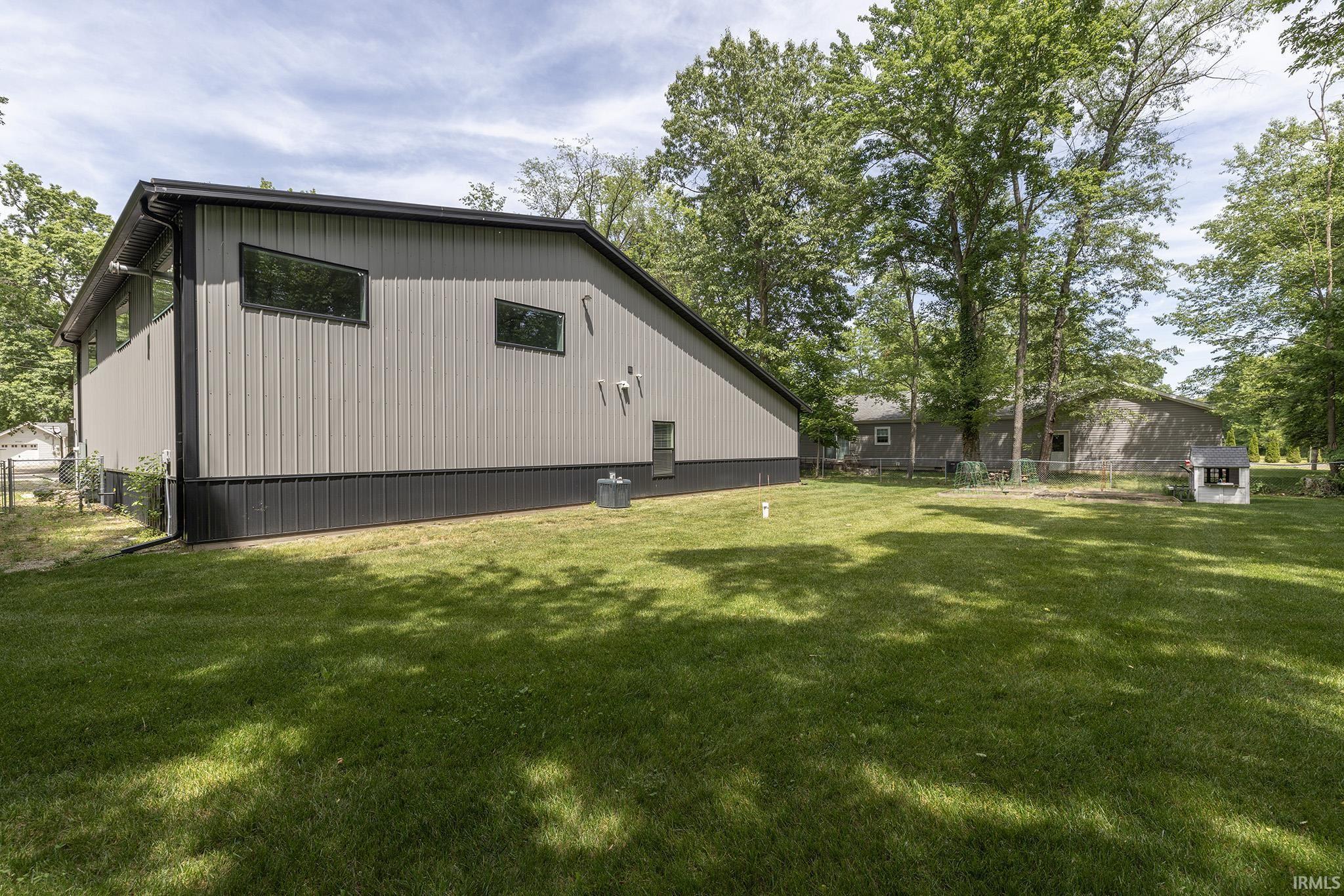 Image 2: Expansive green lawn bordering a modern-style structure with corrugated metal siding, black trim, and unique angled windows, Back Of Structure
