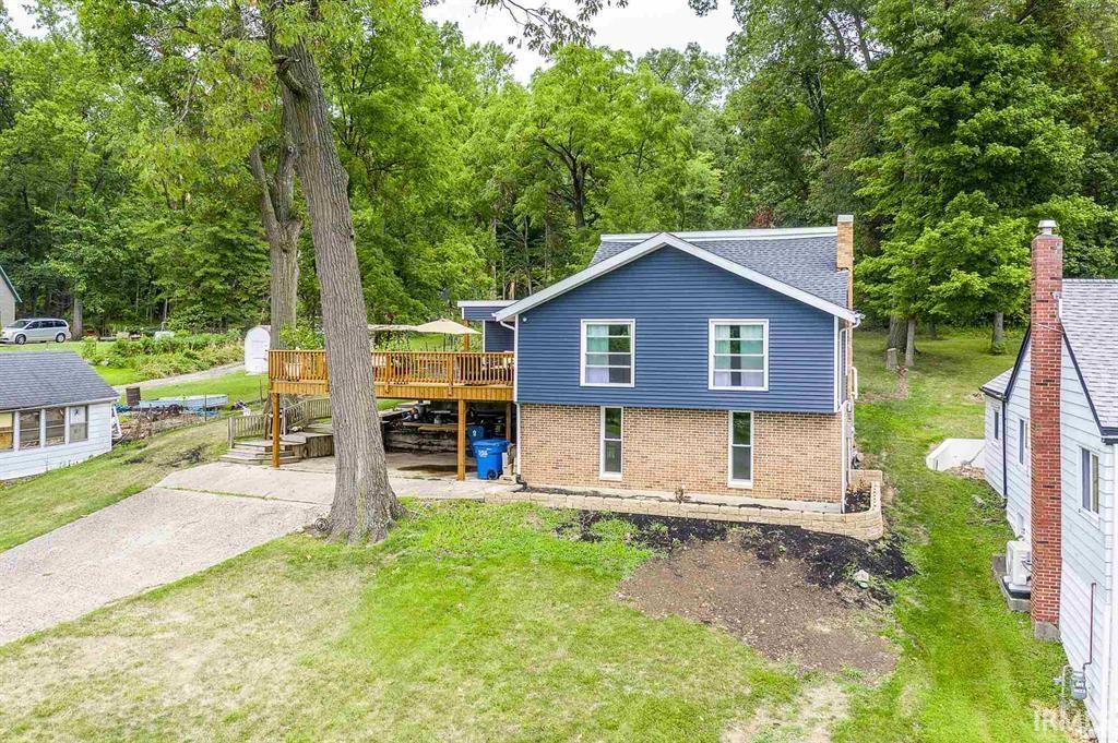 Image 2: Front of property with a wooden deck, brick siding, a lawn, a patio area, and a chimney, front