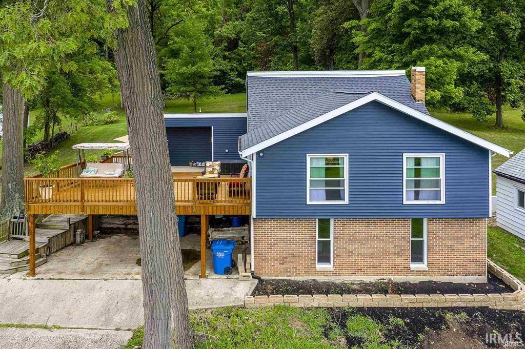 Image 3: front view of property with a chimney, brick siding, a deck, and roof with shingles, front