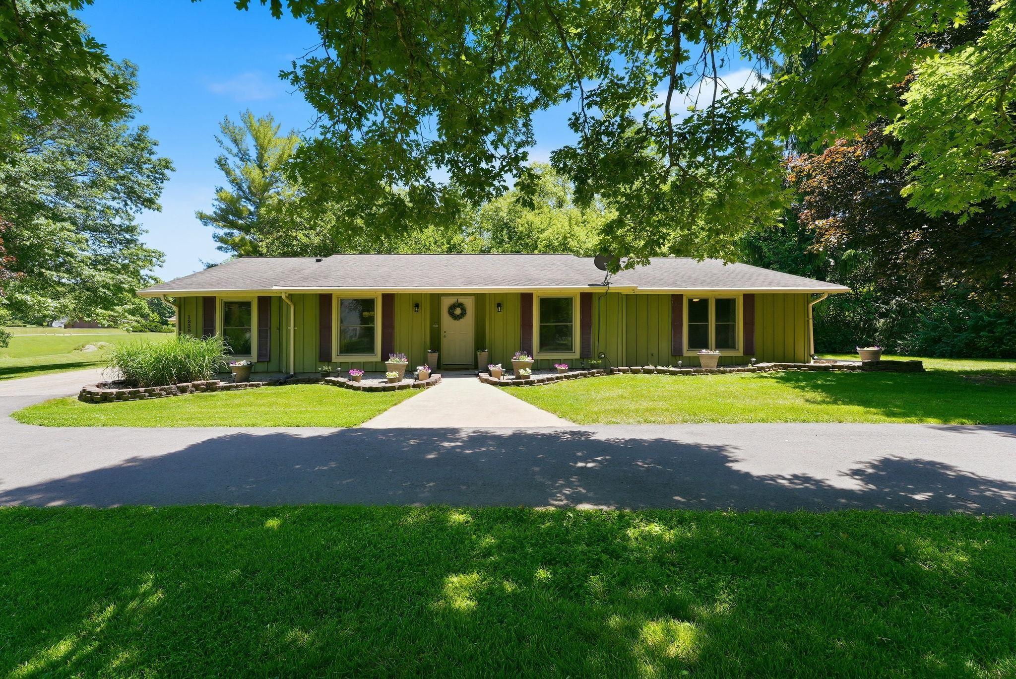 Image 0: Ranch-style exterior with olive green siding, contrasting window shutters, and a central white entry door, Front Of Structure Image 0: Ranch-style exterior with olive green siding, contrasting window shutters, and a central white entry door, Front Of Structure