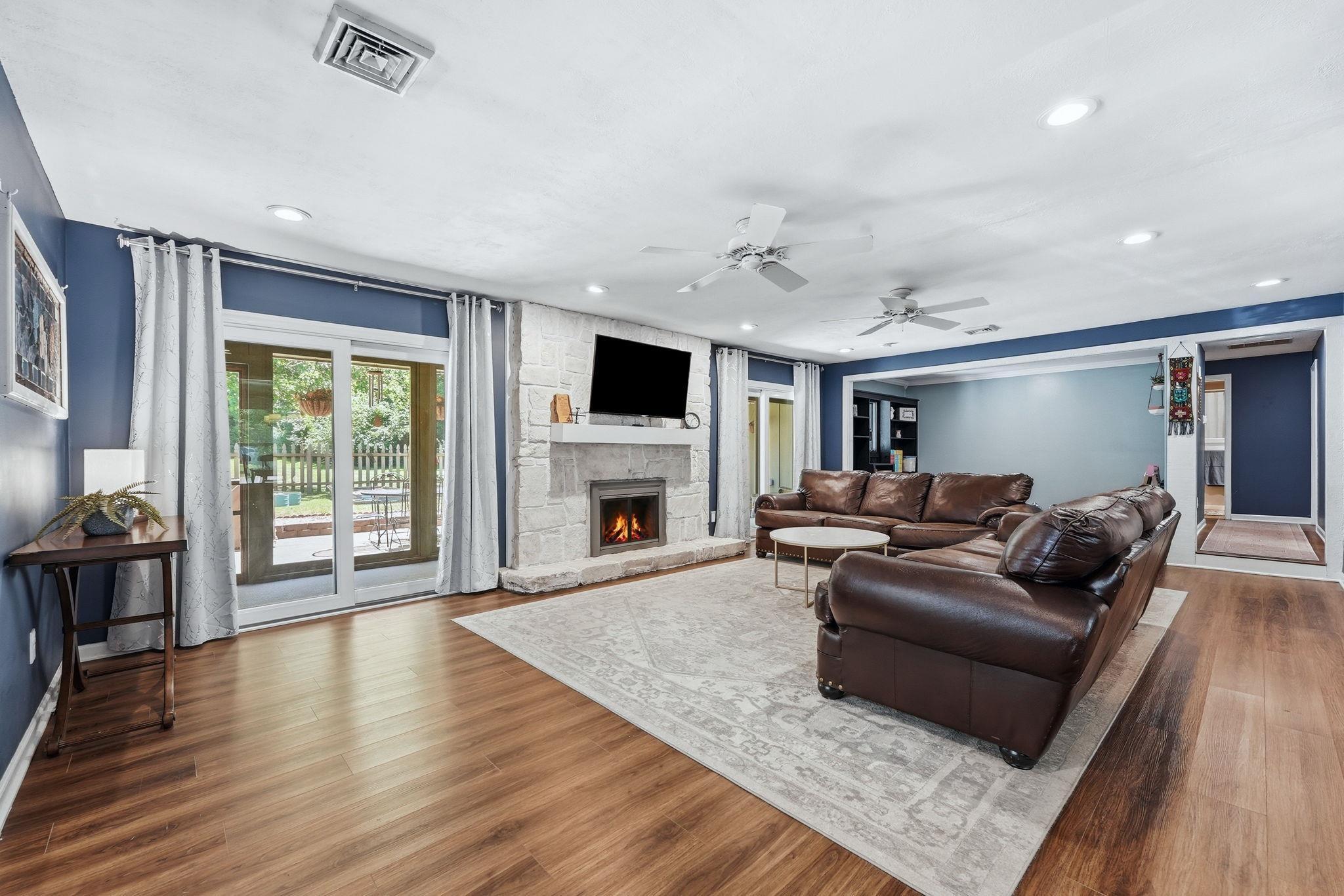 Image 2: Living area featuring wood-finish flooring, a stone-clad fireplace with a hearth, and recessed lighting, Living Room Image 2: Living area featuring wood-finish flooring, a stone-clad fireplace with a hearth, and recessed lighting, Living Room