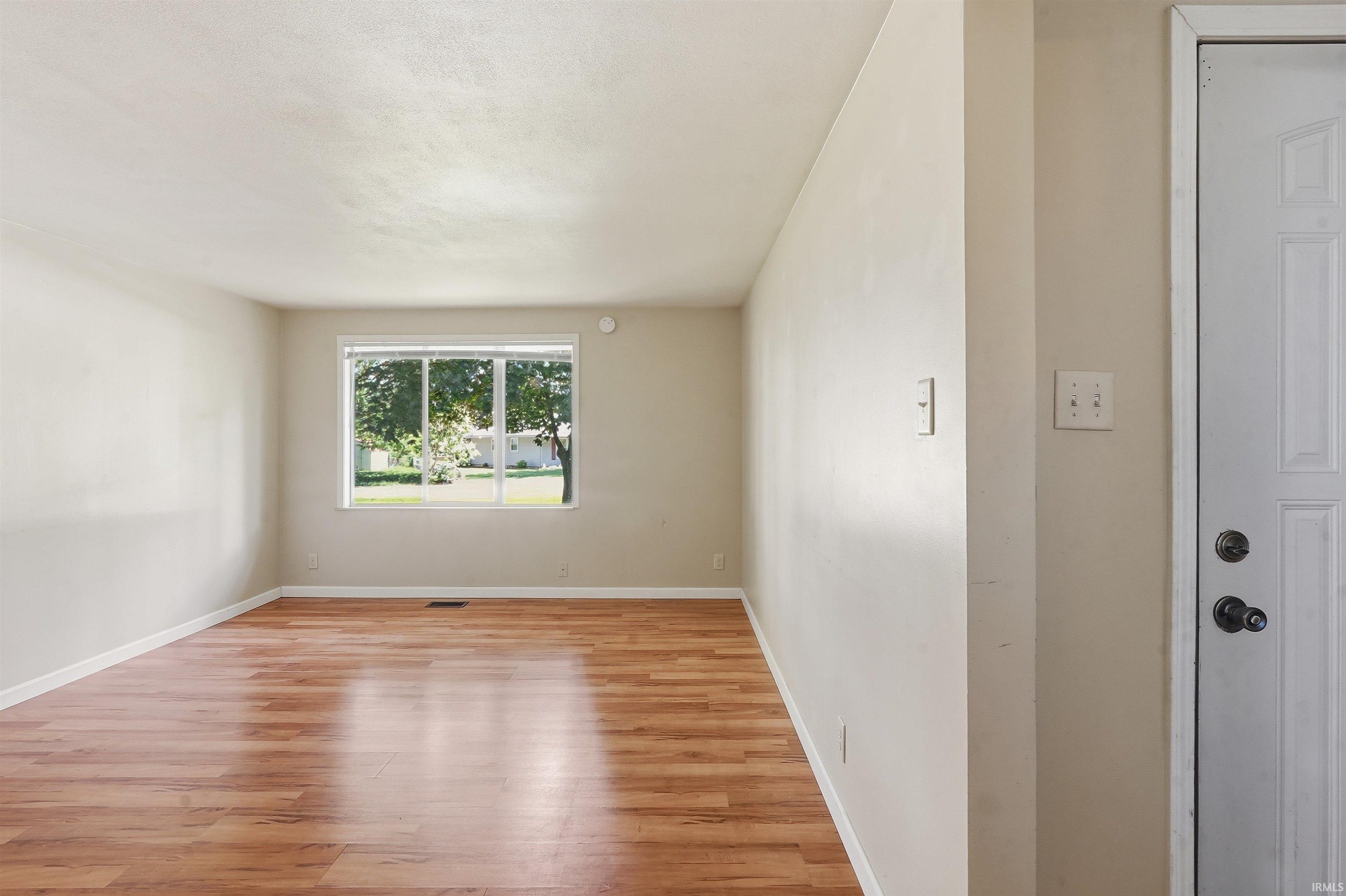 Image 3: Spacious room with wood-finish flooring, neutral wall tones, white trim, and a large window providing ample natural light, Other Image 3: Spacious room with wood-finish flooring, neutral wall tones, white trim, and a large window providing ample natural light, Other