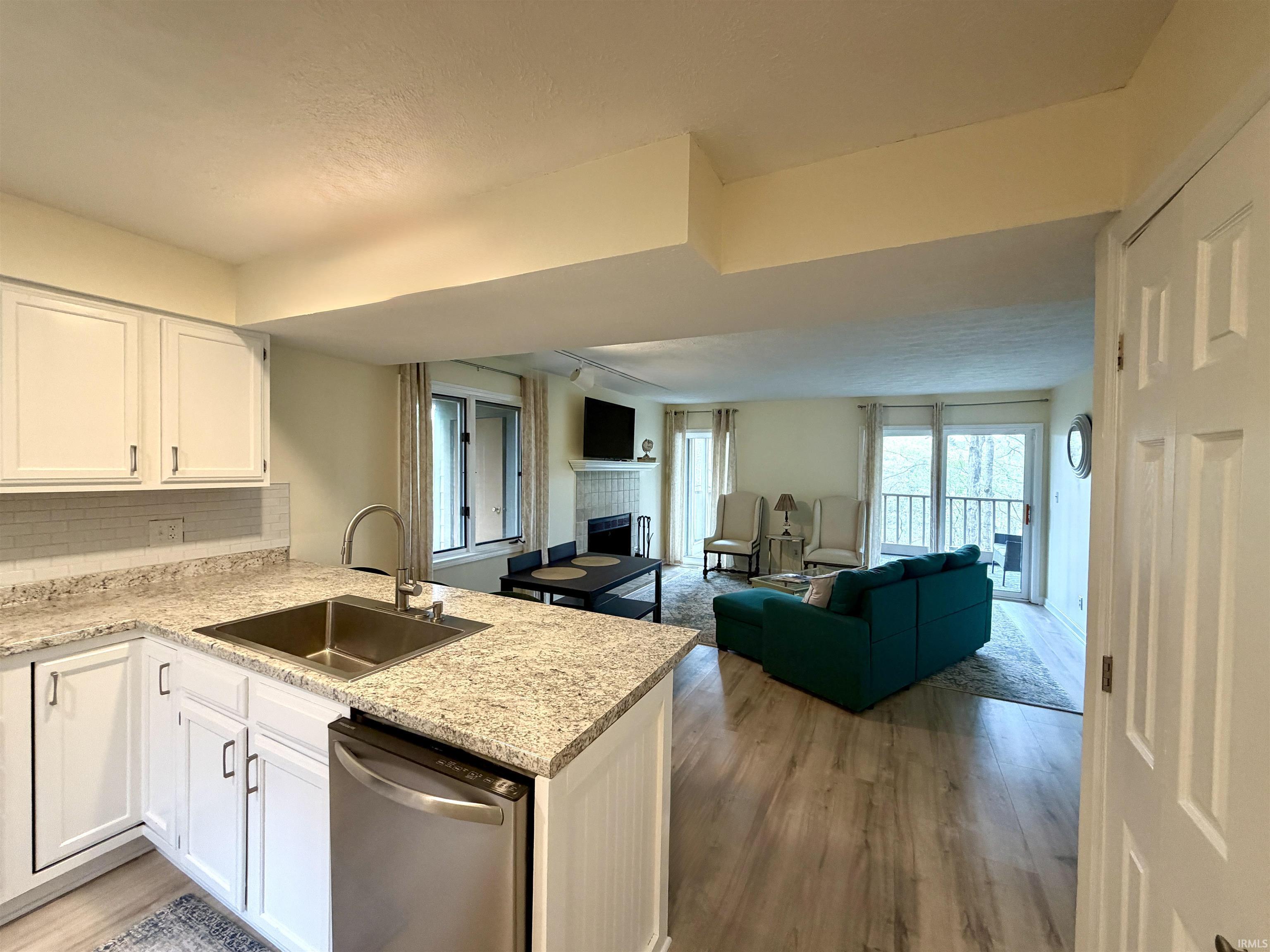 Image 3: Kitchen with open floor plan, white cabinetry, dishwasher, and a tiled fireplace, Kitchen