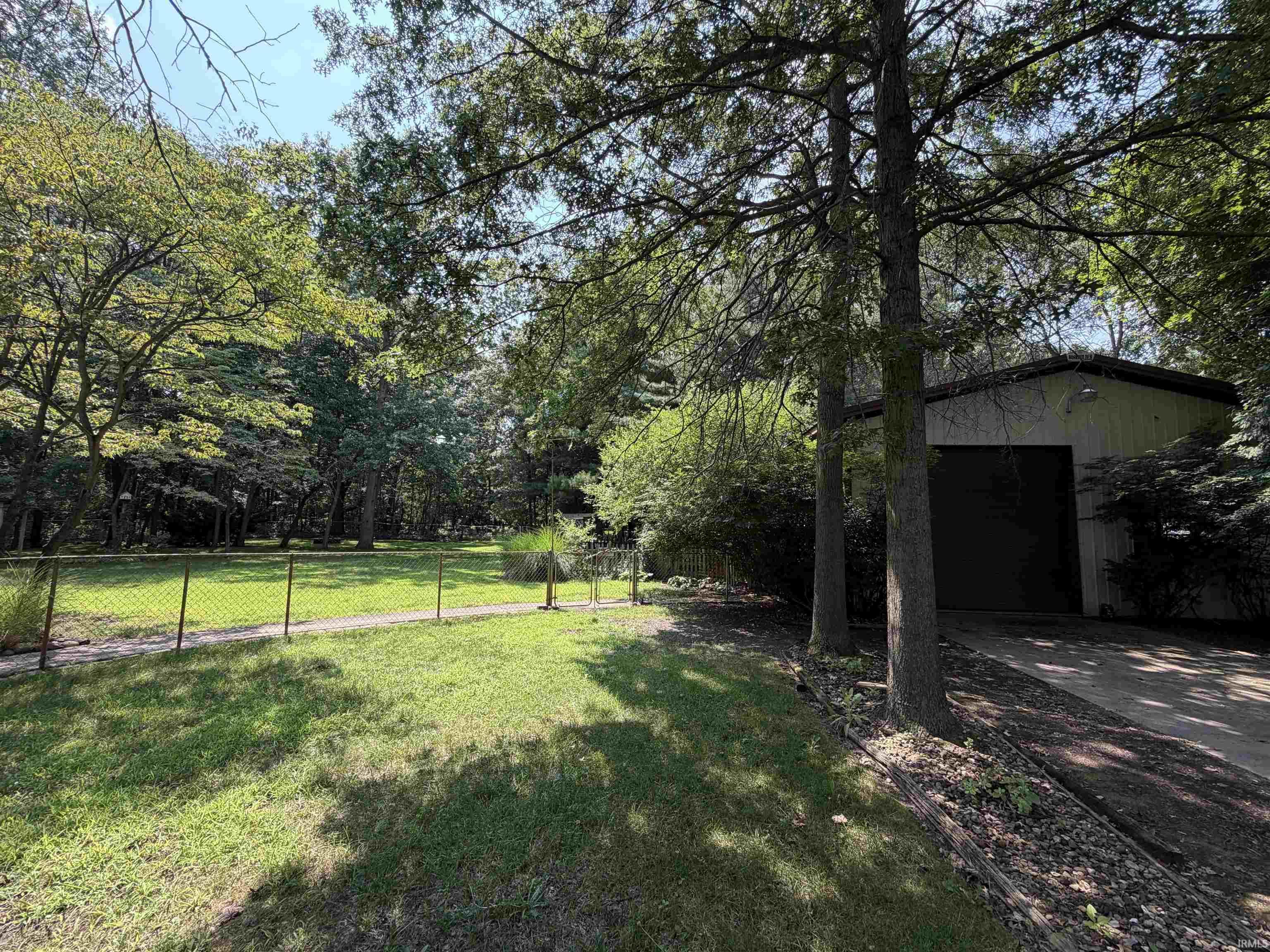 Image 1: Detached garage structure with a large overhead door, positioned on a paved driveway, Yard Image 1: Detached garage structure with a large overhead door, positioned on a paved driveway, Yard