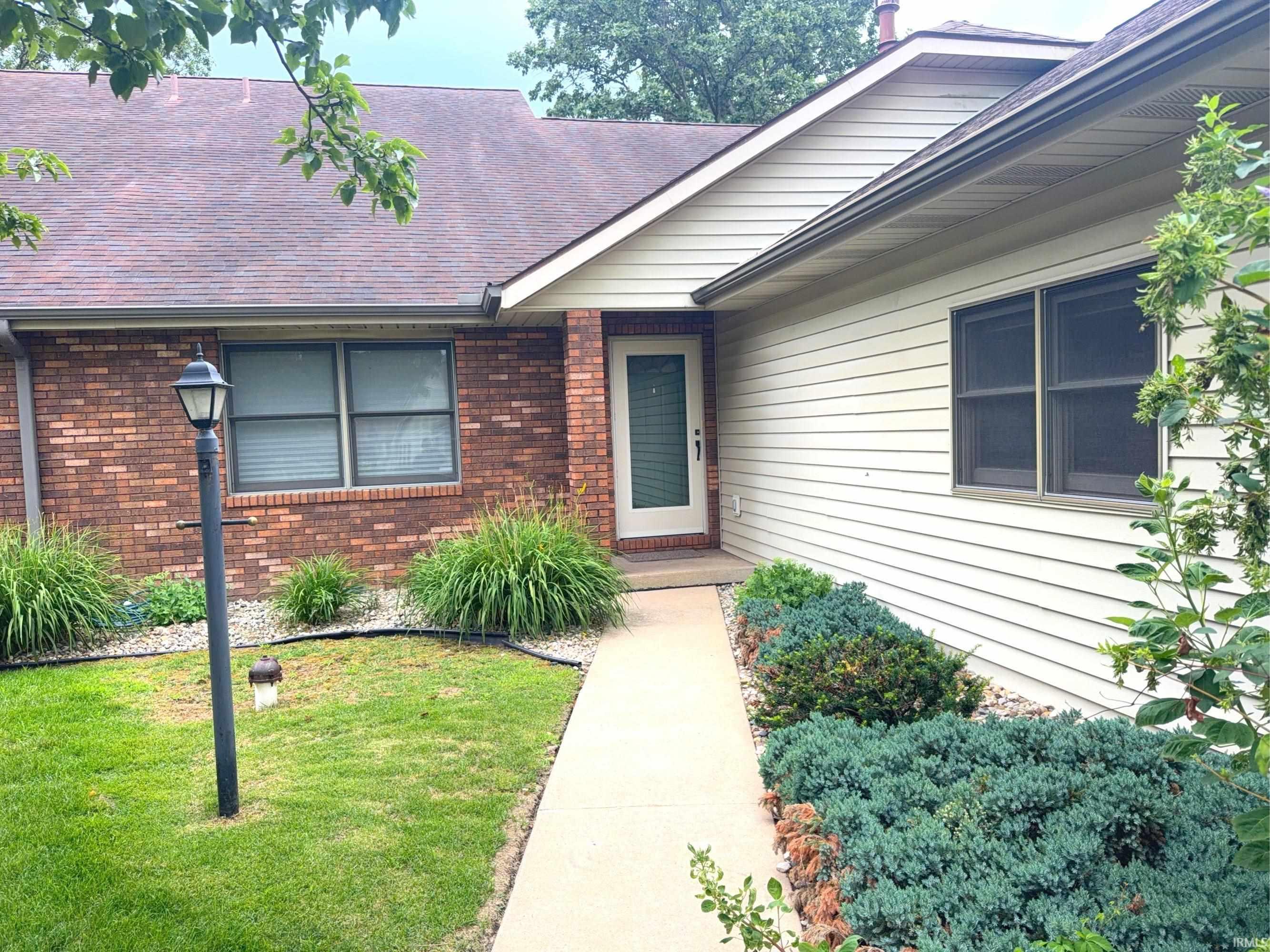 Image 1: Entryway featuring brick and siding exterior, a front door with an integrated screen, and a concrete pathway, Entry Image 1: Entryway featuring brick and siding exterior, a front door with an integrated screen, and a concrete pathway, Entry