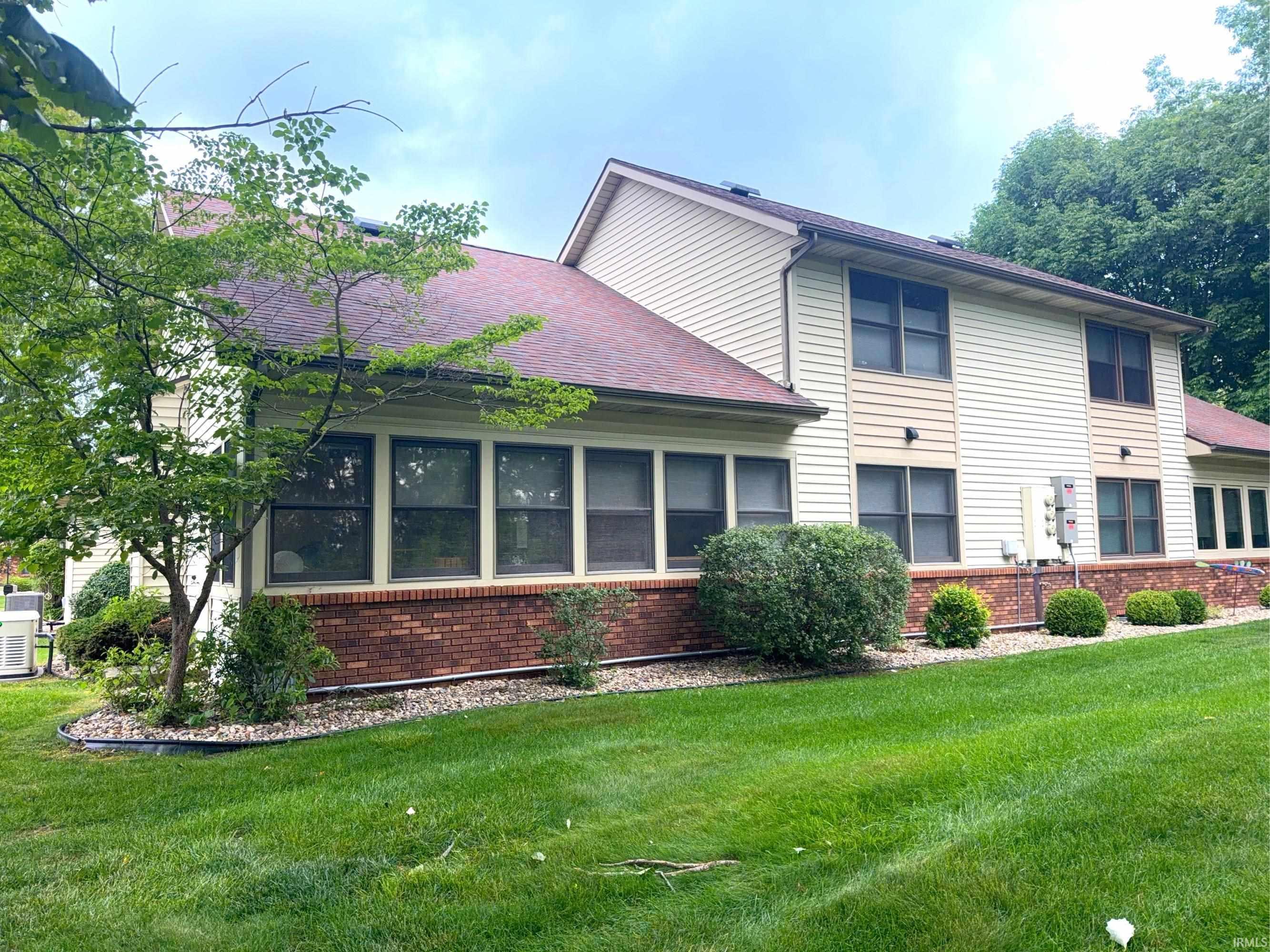 Image 2: Exterior featuring multi-level architecture with brick and siding finishes, multiple windows, a sloped shingle roof, and mature perimeter trees, Back Of Structure Image 2: Exterior featuring multi-level architecture with brick and siding finishes, multiple windows, a sloped shingle roof, and mature perimeter trees, Back Of Structure