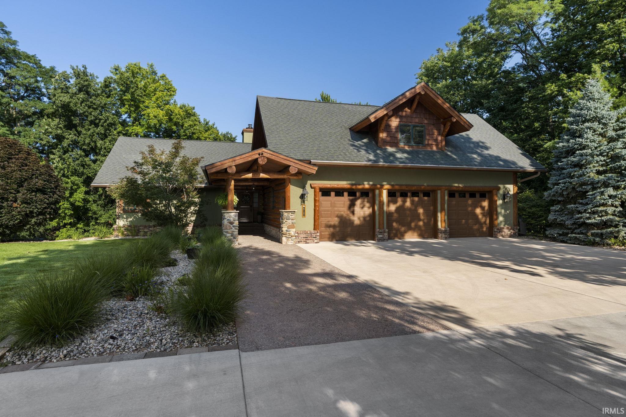 Image 3: Craftsman-style home featuring a prominent three-car garage with wood-finish doors, Front Of Structure