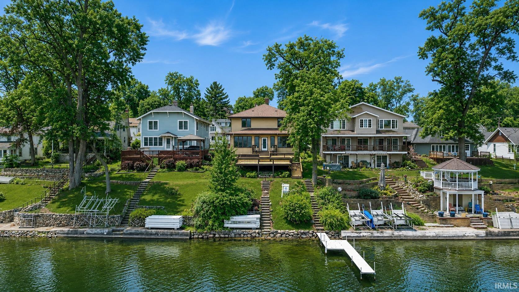 Image 0: Waterfront property featuring a private dock, multiple boat lifts, and tiered landscaping with stone steps, Back Of Structure Image 0: Waterfront property featuring a private dock, multiple boat lifts, and tiered landscaping with stone steps, Back Of Structure