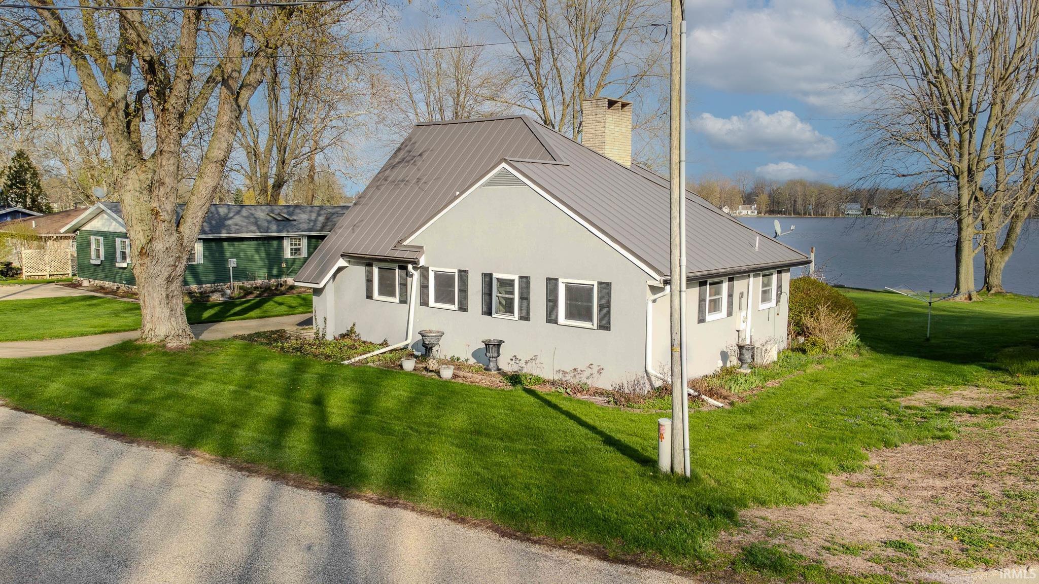 Image 2: View of front of home featuring a chimney, a front yard, and a metal roof, Front Of Structure Image 2: View of front of home featuring a chimney, a front yard, and a metal roof, Front Of Structure
