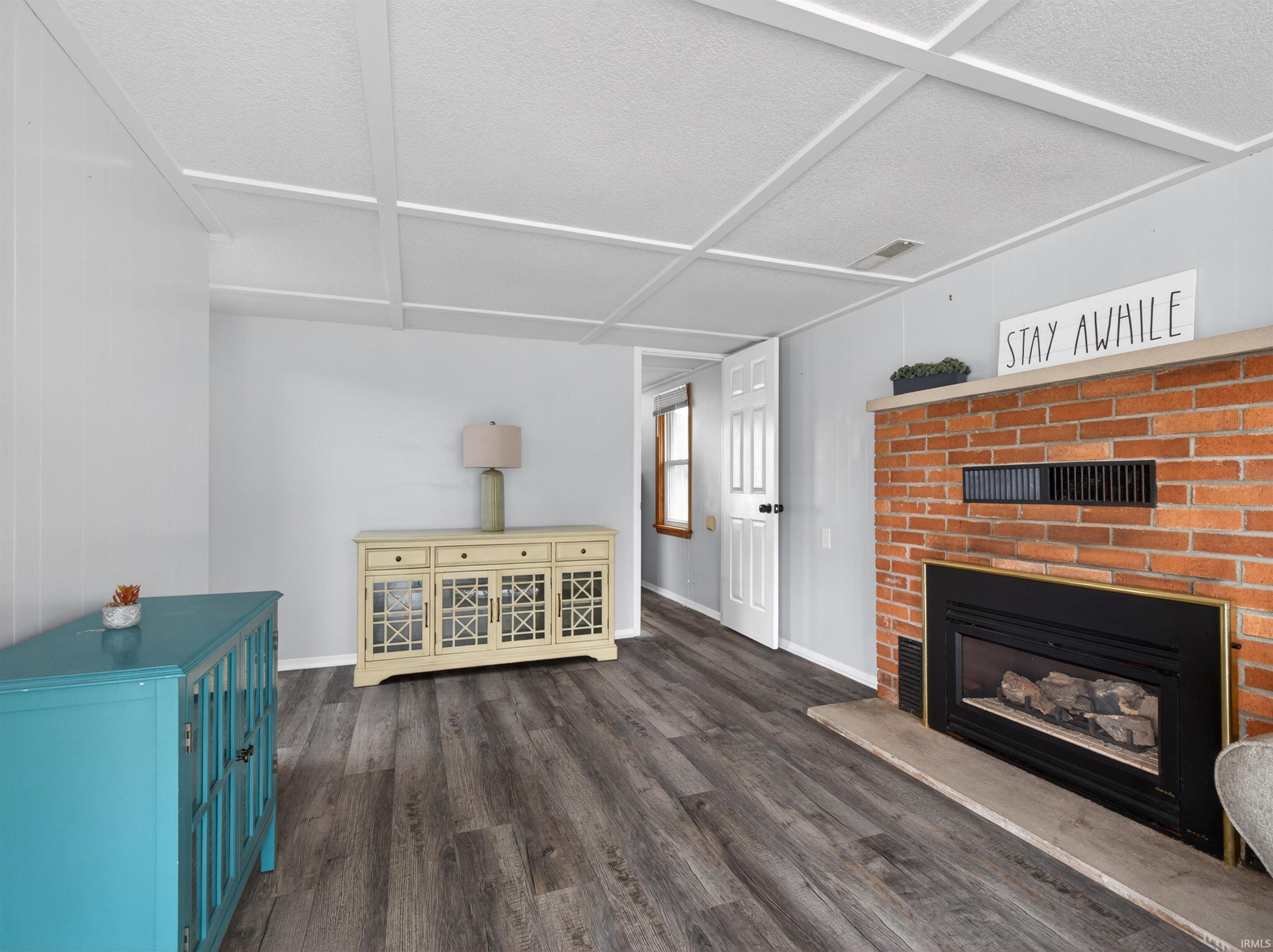 Image 3: Living area with dark wood-type flooring and a fireplace, Living Room
