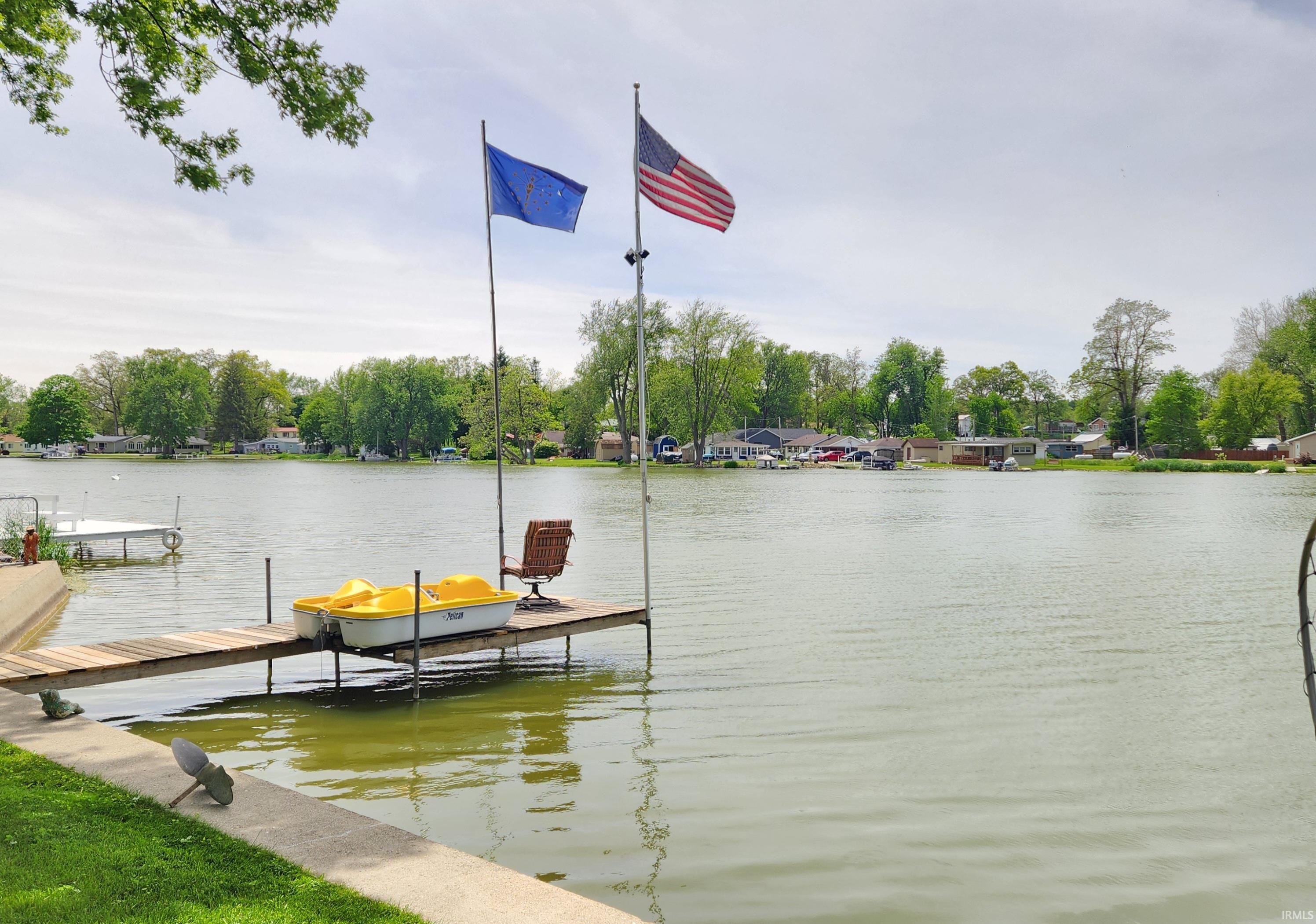 Image 2: Waterfront property featuring a private dock, green lawn bordering the water, and mature trees across the lake, Dock Image 2: Waterfront property featuring a private dock, green lawn bordering the water, and mature trees across the lake, Dock