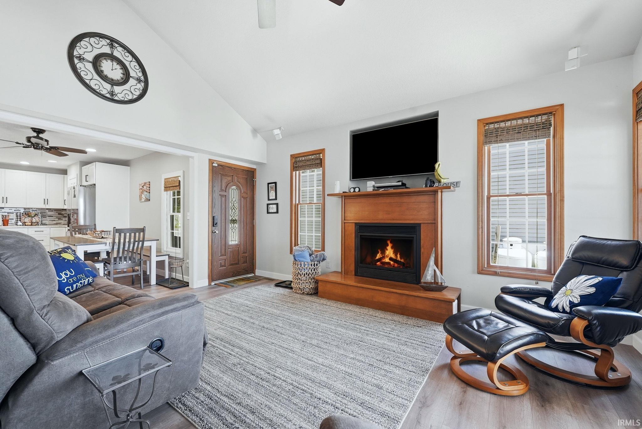 Image 1: Living area featuring wood-finish flooring, a contemporary fireplace with a wooden mantel, and vaulted ceilings, Living Room Image 1: Living area featuring wood-finish flooring, a contemporary fireplace with a wooden mantel, and vaulted ceilings, Living Room