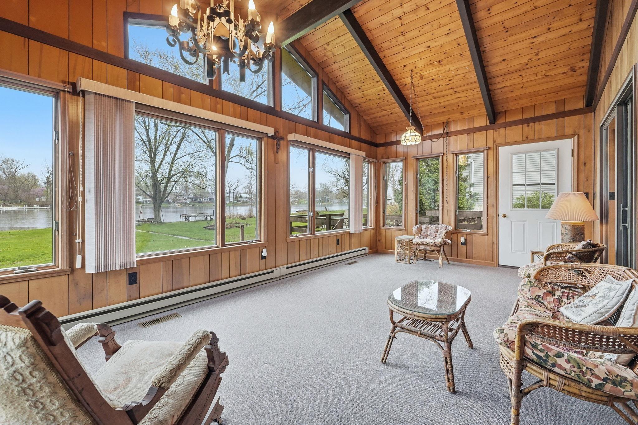 Image 3: Sunroom with wood walls, suspended lighting, carpet, a baseboard heating unit, and a high wood beamed ceiling, Family Room Image 3: Sunroom with wood walls, suspended lighting, carpet, a baseboard heating unit, and a high wood beamed ceiling, Family Room