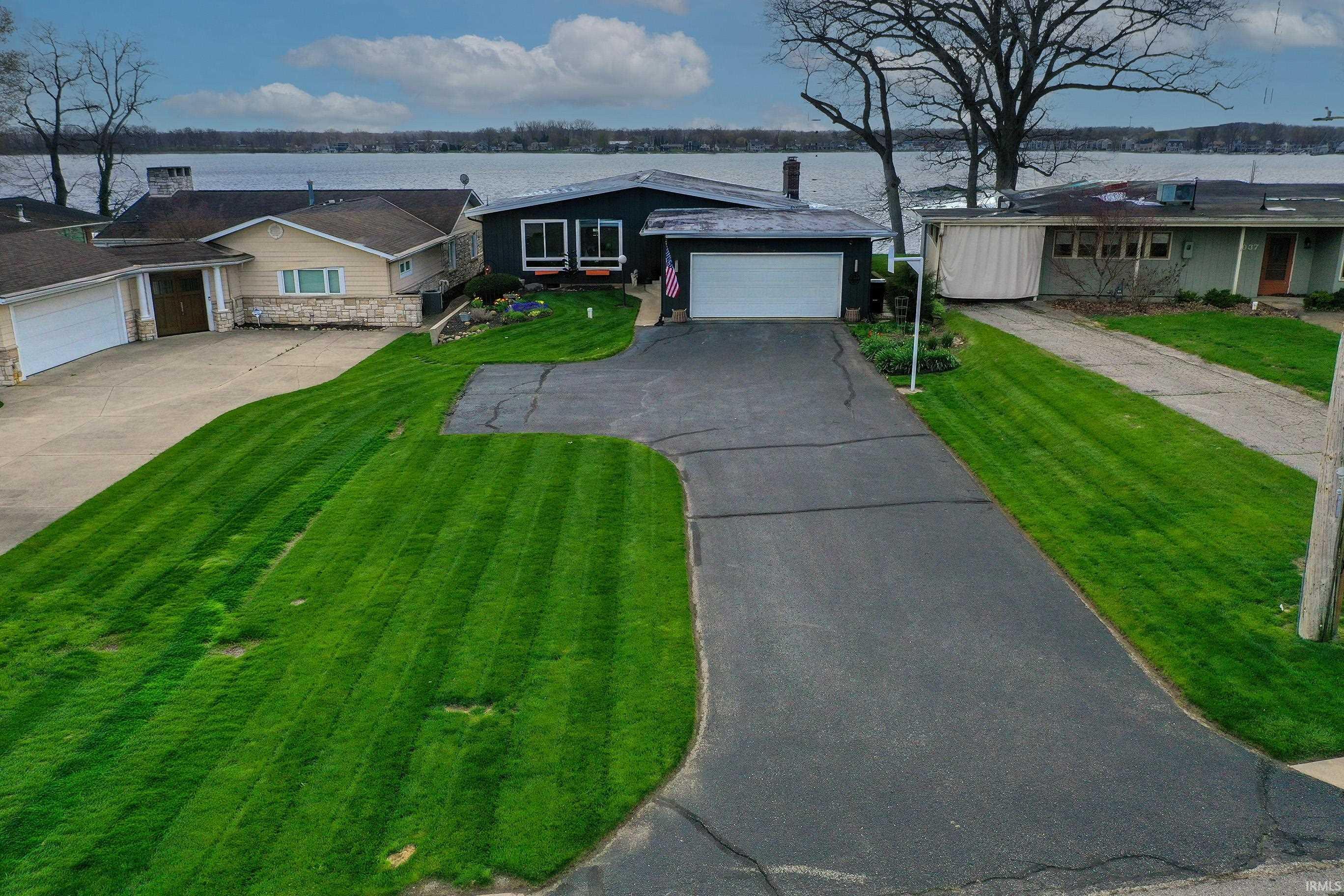 Image 1: Single story home featuring a front lawn, driveway, and a water view, Front Of Structure Image 1: Single story home featuring a front lawn, driveway, and a water view, Front Of Structure