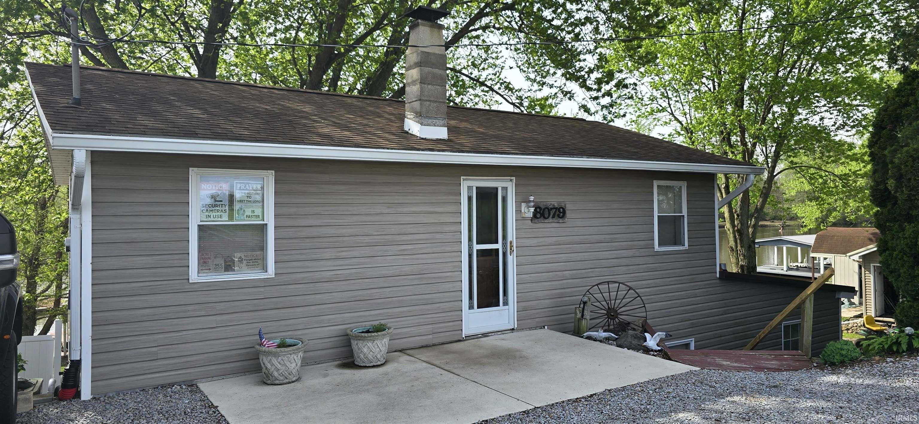 Image 1: Rear view of property with a patio, roof with shingles, and a chimney, Back Of Structure