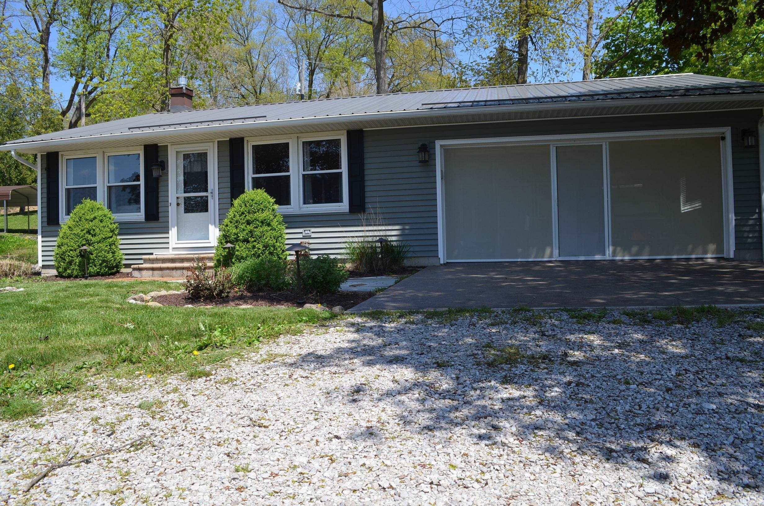 Image 0: Ranch-style exterior with blue siding, metal roof, and a screened garage entry, Front Of Structure