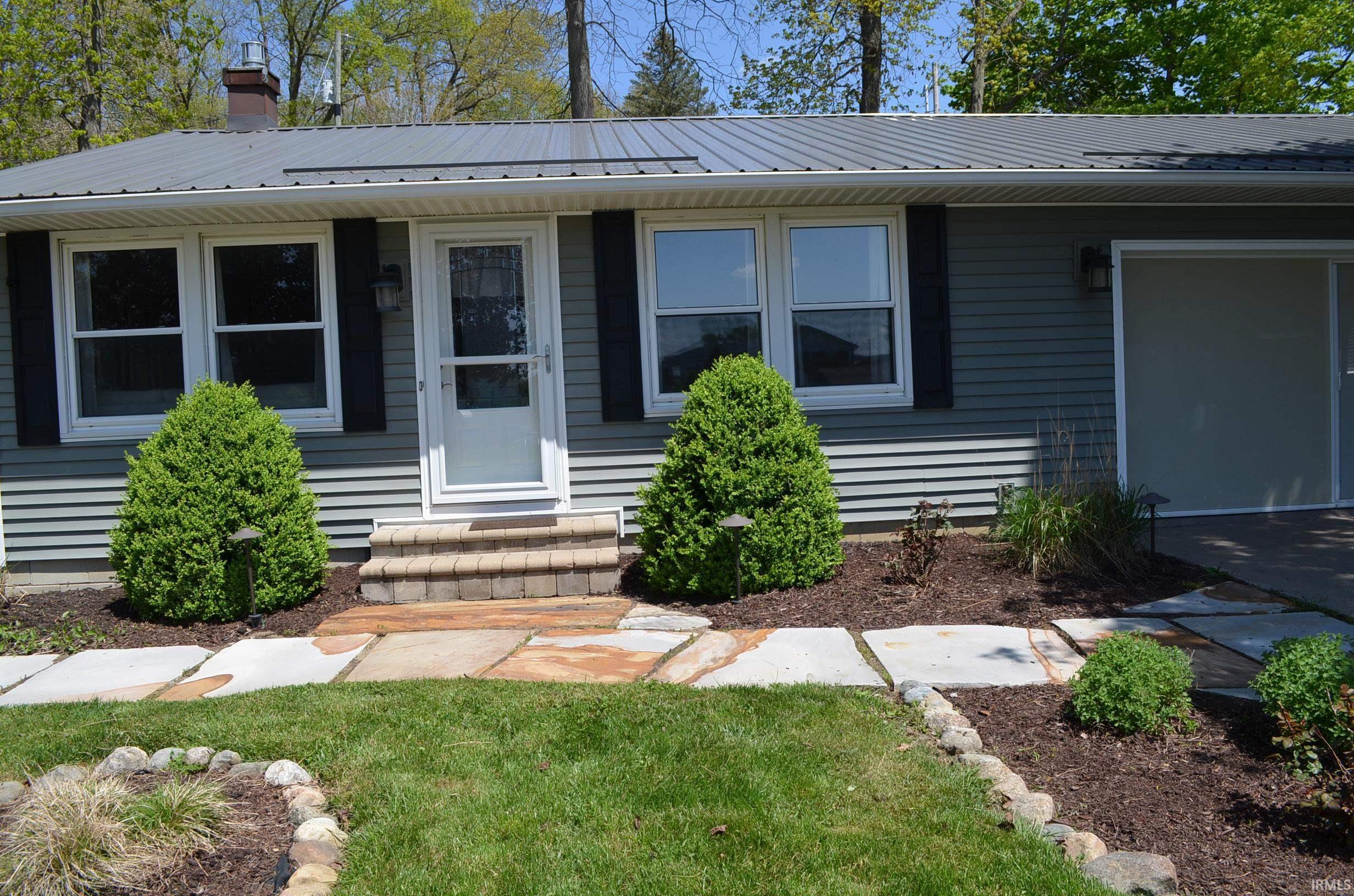Image 1: Exterior with blue siding and a metal roof, front