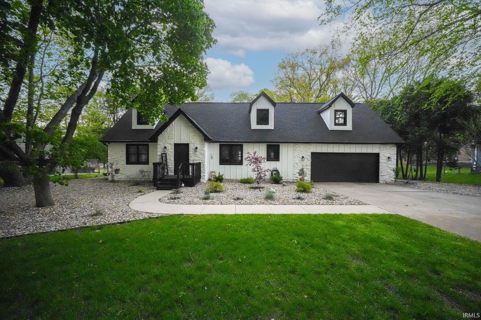 Image 0: White-paneled exterior with black trim windows, a black garage door, and a dark shingled roof, Front Of Structure