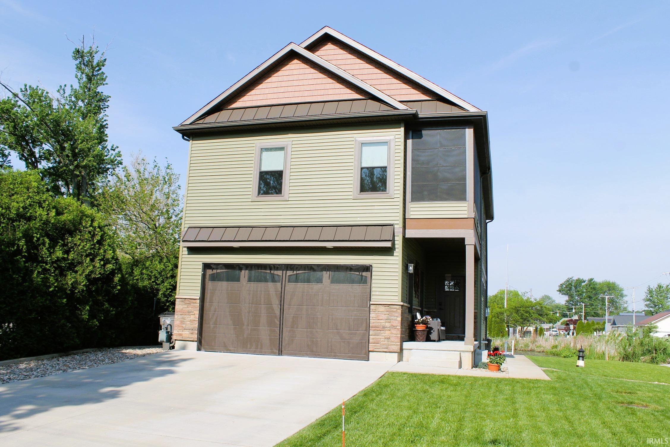 Image 1: Two-story residence featuring light green horizontal siding and stacked stone accents, Front Of Structure