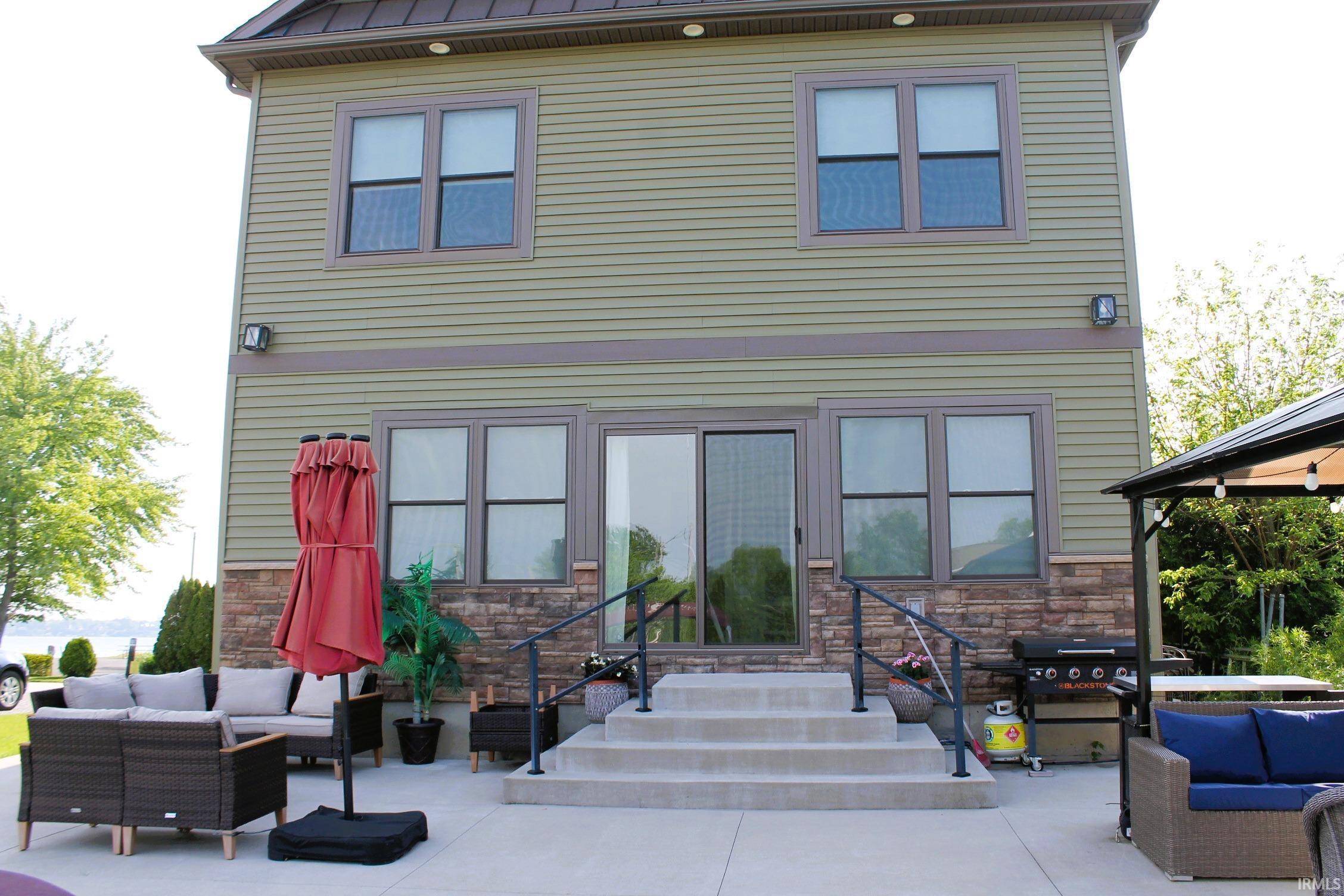 Image 3: Rear exterior of a two-story residence featuring horizontal siding and stone veneer, Back Patio