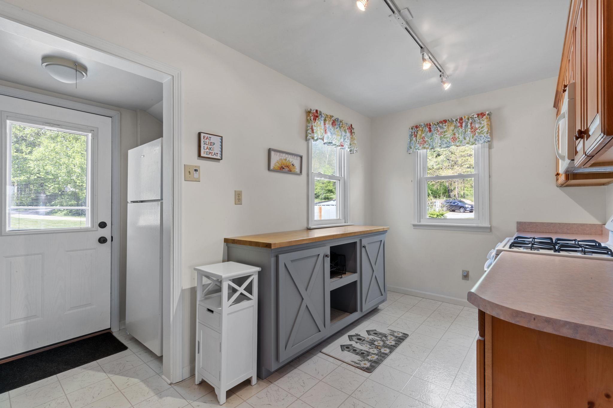 Image 3: Kitchen featuring a grey-painted island with a wood countertop, a built-in range, wood cabinetry, and track lighting, Kitchen Image 3: Kitchen featuring a grey-painted island with a wood countertop, a built-in range, wood cabinetry, and track lighting, Kitchen