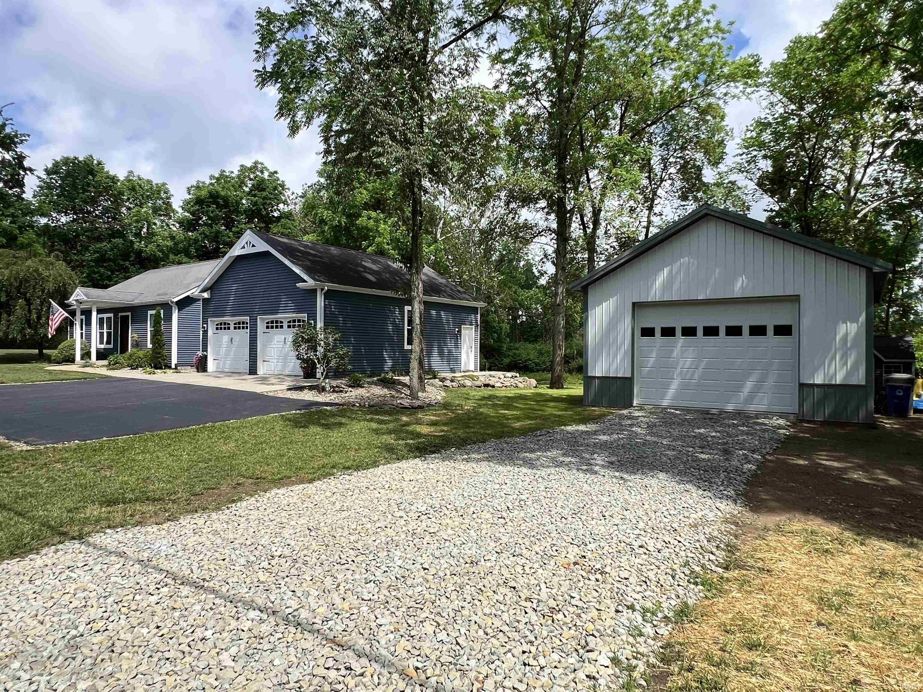 Image 0: Detached garage building with a single overhead door, complemented by a main residence featuring blue siding, a covered entry, and an attached two-car garage, 6572 E South Barbee Dr