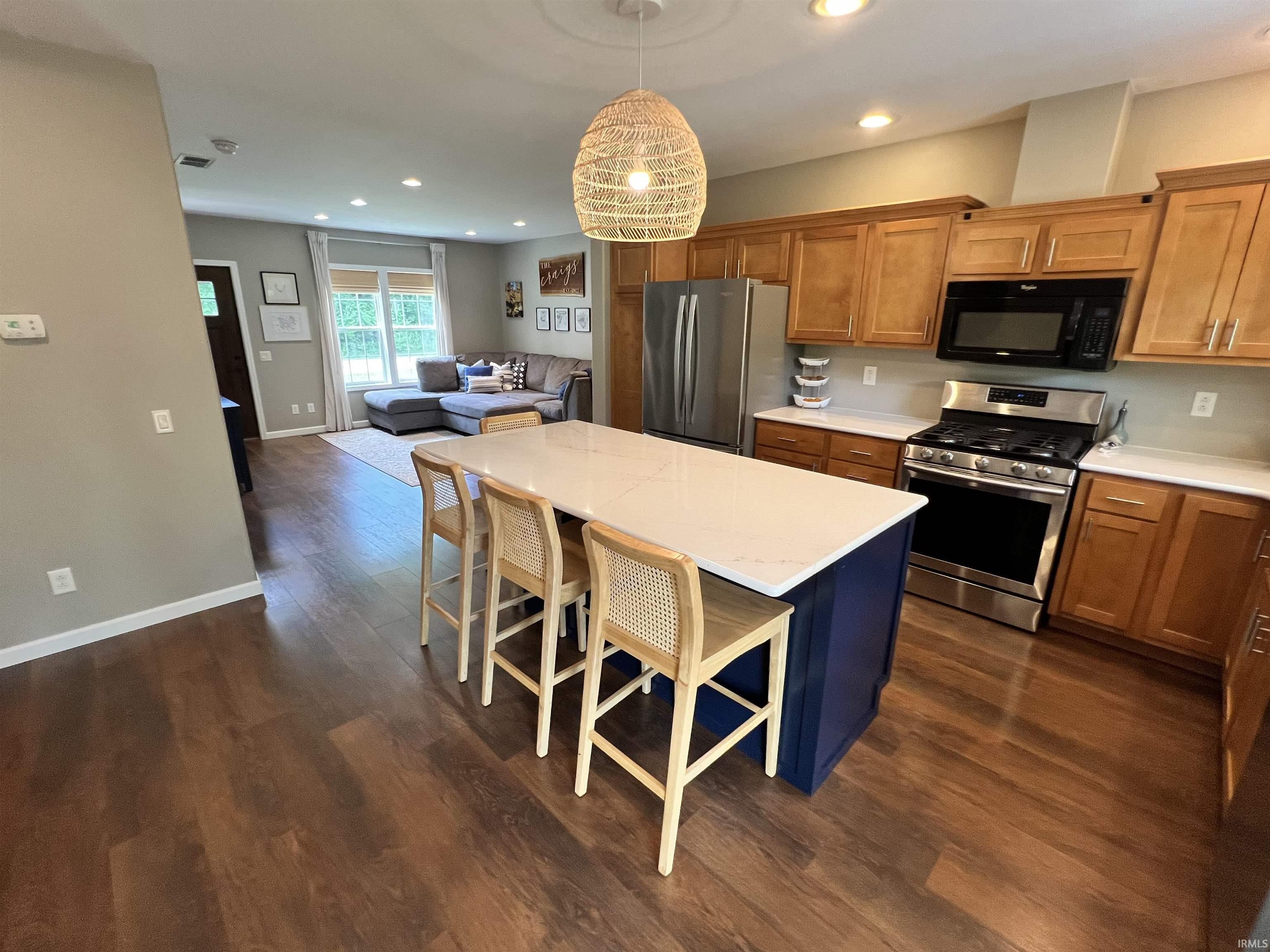 Image 1: Kitchen featuring a central island with white countertop, wood-finish flooring, stainless steel appliances, wood cabinetry, and recessed lighting, Kitchen