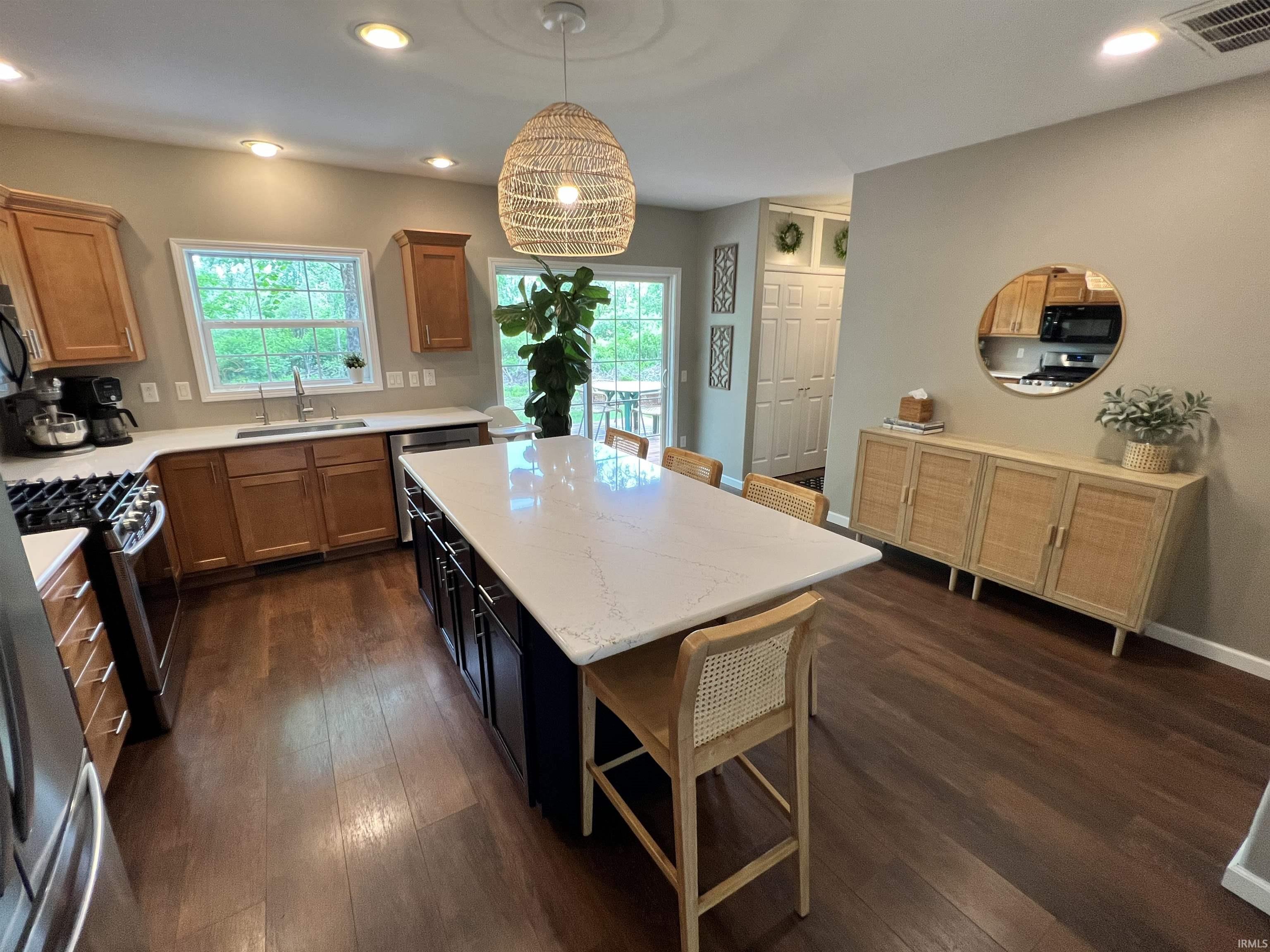 Image 2: Kitchen featuring a large central island with a light-toned countertop, stainless steel appliances, wood-finish flooring, and light-stained cabinetry, Kitchen