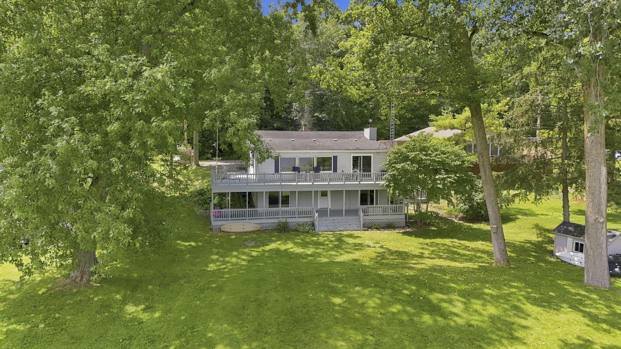 Image 0: Two-story residence featuring a large upper-level deck, lower-level patio, and a verdant lawn, Back Of Structure Image 0: Two-story residence featuring a large upper-level deck, lower-level patio, and a verdant lawn, Back Of Structure