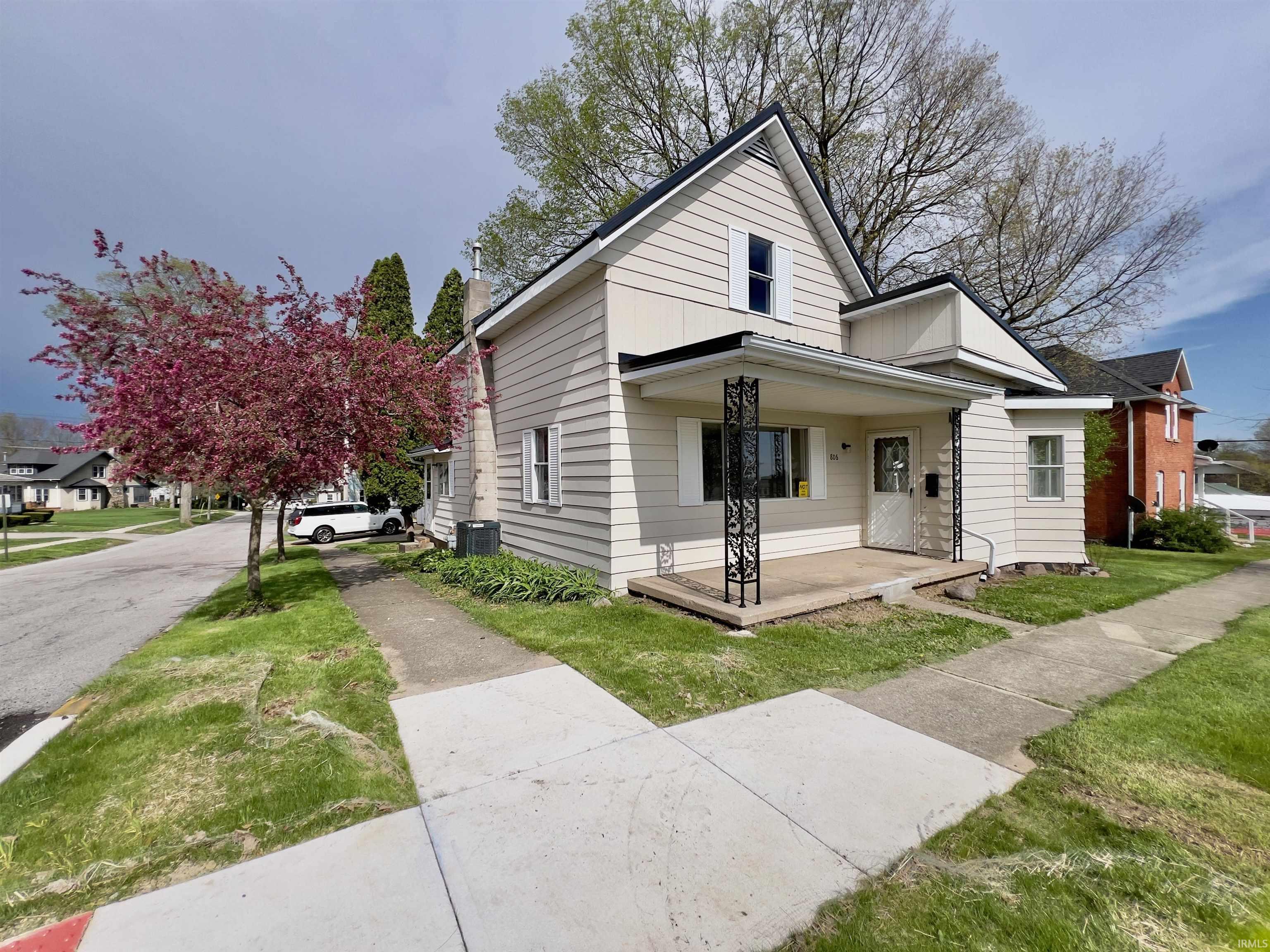 Image 0: Light-colored siding exterior featuring a covered front porch with decorative black metal columns, Front Of Structure Image 0: Light-colored siding exterior featuring a covered front porch with decorative black metal columns, Front Of Structure