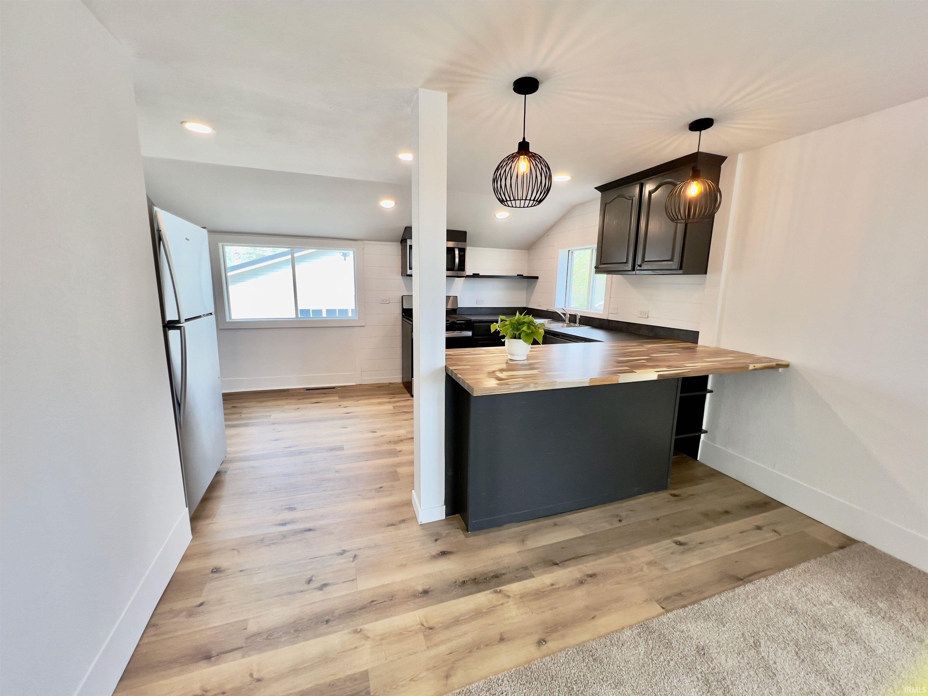Image 3: Kitchen featuring a breakfast bar with a butcher clock countertop, dark cabinetry, recessed downlight and two contemporary pendant lights, Kitchen Image 3: Kitchen featuring a breakfast bar with a butcher clock countertop, dark cabinetry, recessed downlight and two contemporary pendant lights, Kitchen