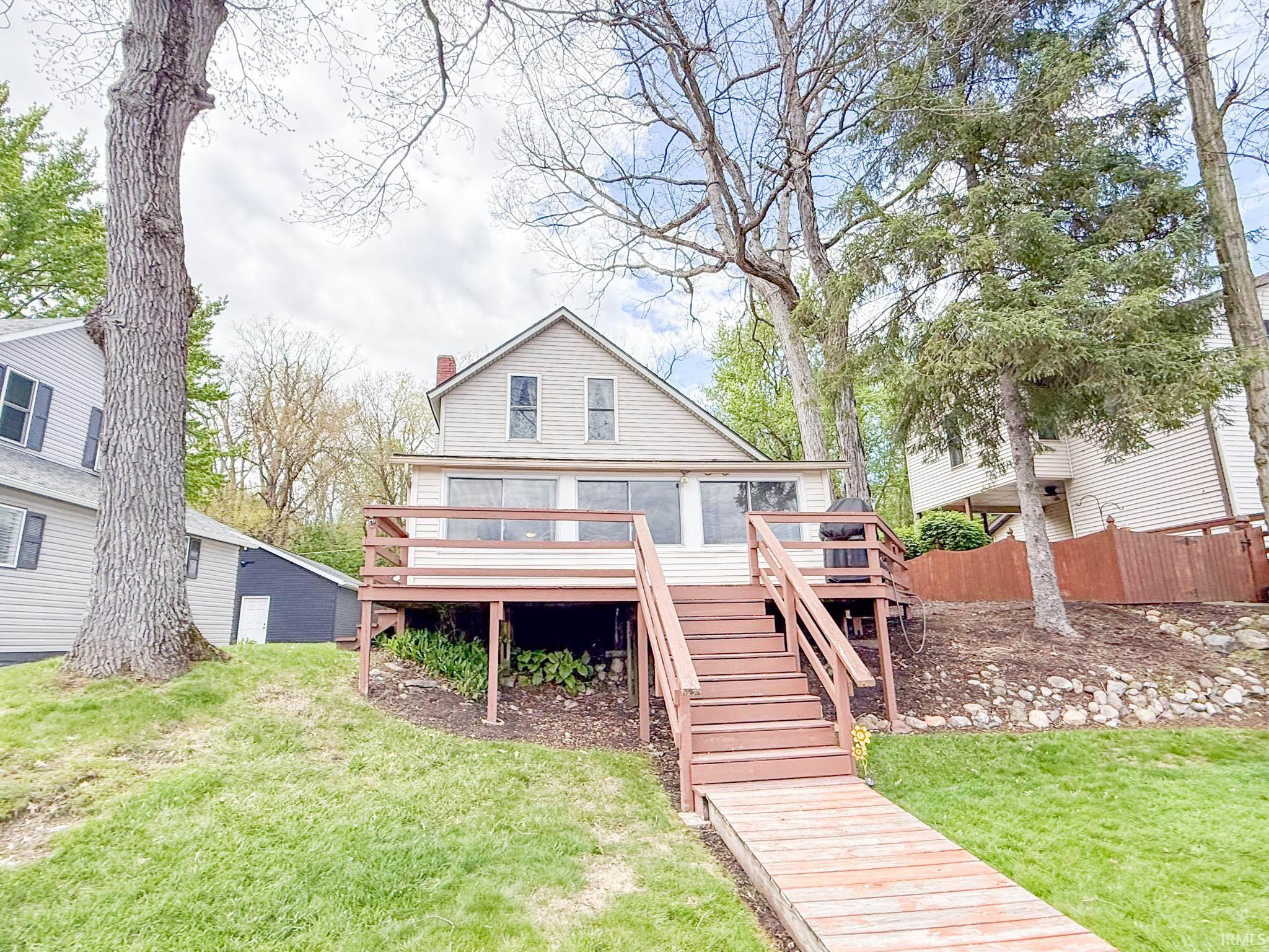 Image 0: Waterfront property featuring a wood dock, multi-level exterior deck, and a spacious green lawn, Back Of Structure