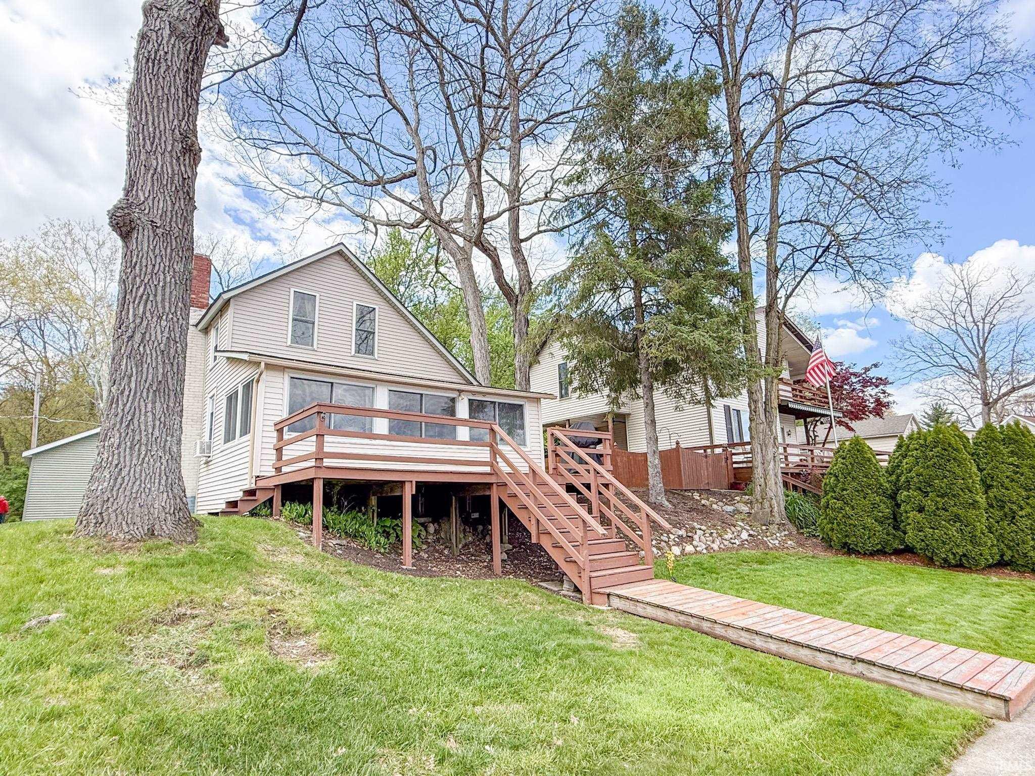 Image 1: Exterior featuring a spacious deck with railing, a pedestrian ramp, and mature trees, Back Of Structure