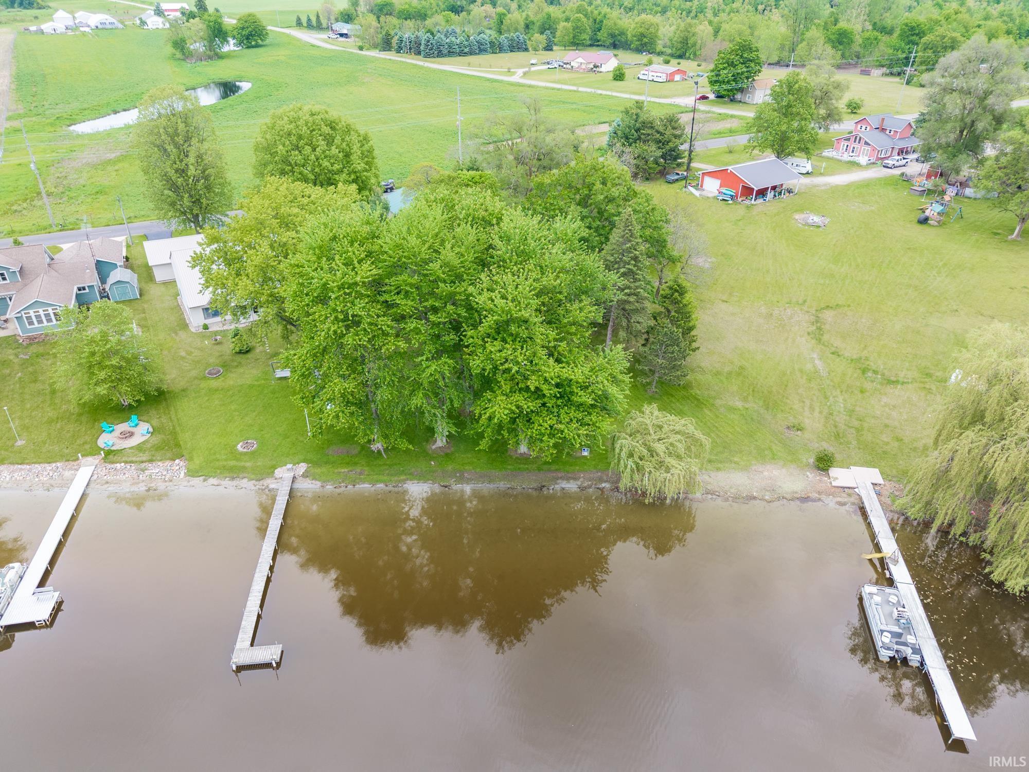 Image 0: Waterfront property featuring multiple docks, lush green landscaping, and mature trees, 150 ft Lakefront home on .68 acre lot with brick remodeled home and a 30x40 pole building for tows