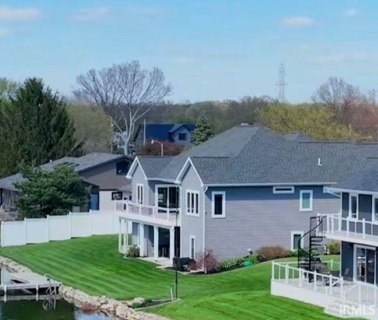 Image 2: Waterfront property featuring a private dock, expansive green lawn, multiple balconies with white railings, and a spiral staircase, Back Of Structure