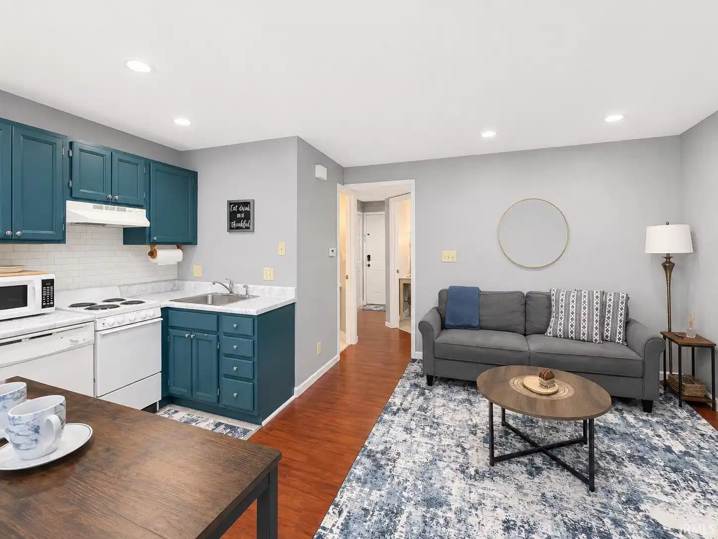 Image 0: Kitchen featuring teal cabinetry, subway tile backsplash, and light-toned countertops, Living Room Image 0: Kitchen featuring teal cabinetry, subway tile backsplash, and light-toned countertops, Living Room