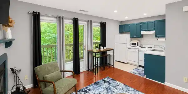 Image 3: Kitchen featuring teal cabinetry with white appliances and a subway tile backsplash, Living Room Image 3: Kitchen featuring teal cabinetry with white appliances and a subway tile backsplash, Living Room