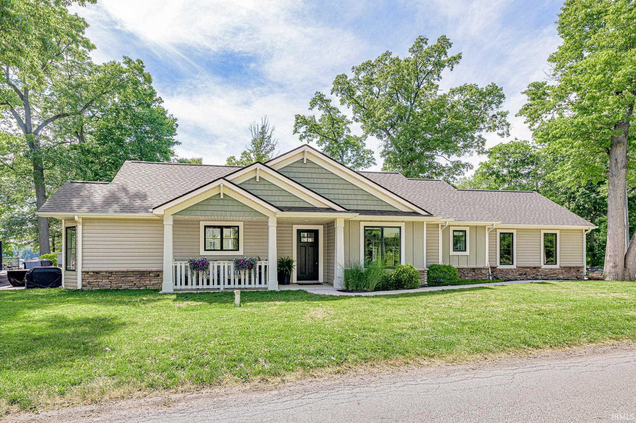 Image 0: Ranch-style residence featuring light-colored siding, a dark asphalt shingle roof, and a stone veneer foundation, Front Of Structure