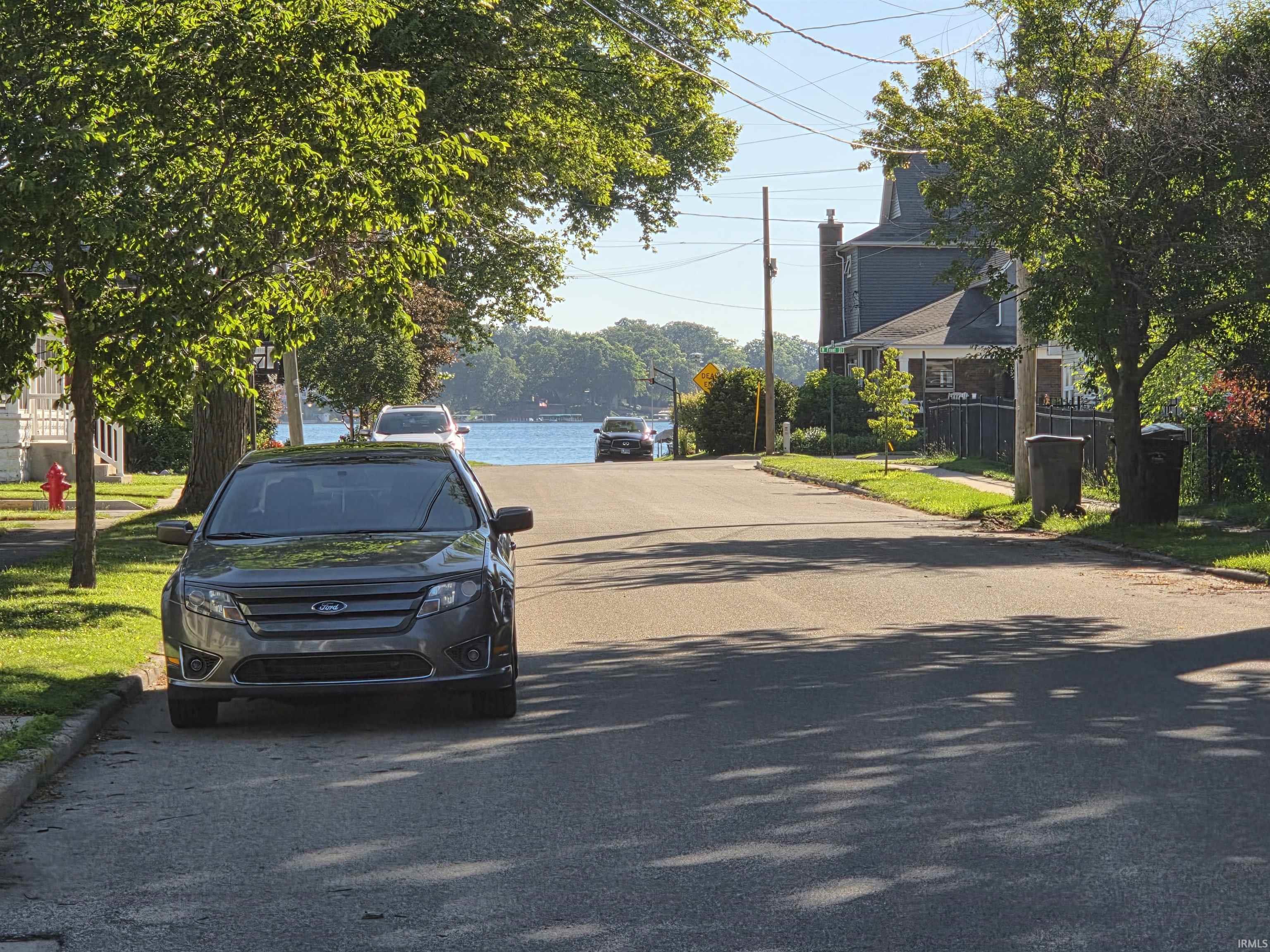 Image 2: Street scene featuring paved road with water visible at the end of the street, 2 blocks from Syracuse Lake! Image 2: Street scene featuring paved road with water visible at the end of the street, 2 blocks from Syracuse Lake!