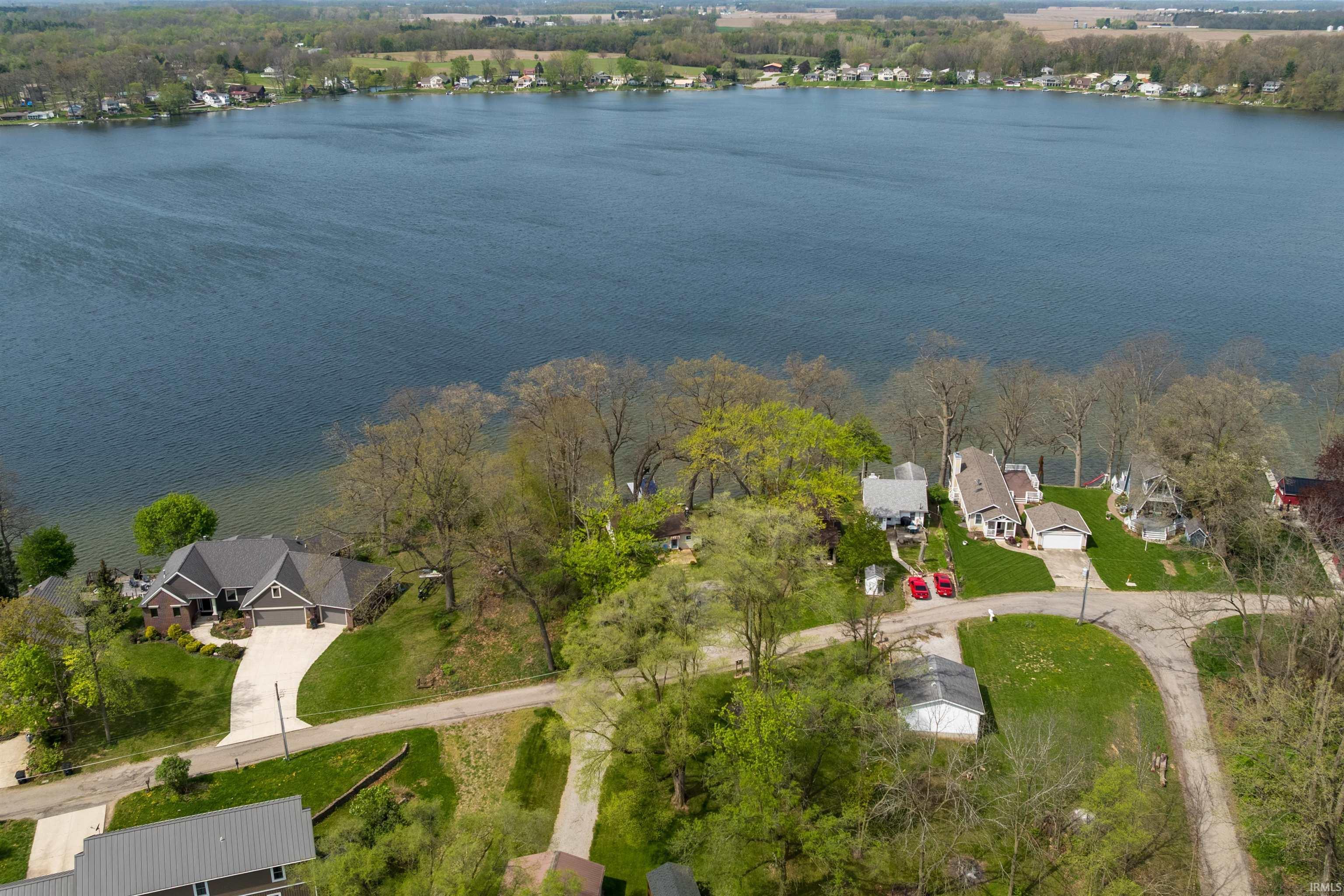 Image 3: Lakefront property featuring a private dock, mature trees, and a paved driveway, Aerial View Image 3: Lakefront property featuring a private dock, mature trees, and a paved driveway, Aerial View