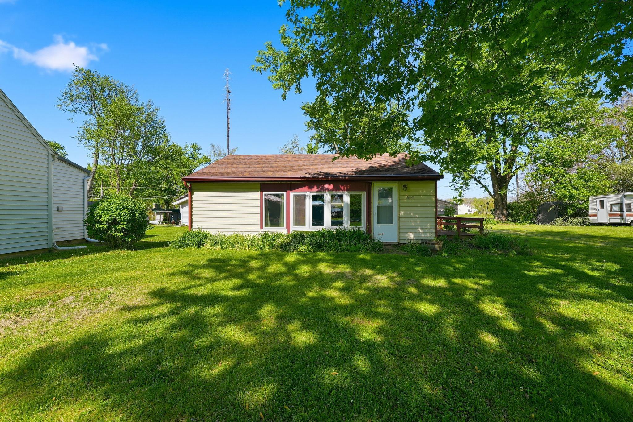 Image 0: Single-story residence featuring light-colored siding, a brown shingle roof, and a prominent sunroom with multiple windows, Back Of Structure Image 0: Single-story residence featuring light-colored siding, a brown shingle roof, and a prominent sunroom with multiple windows, Back Of Structure