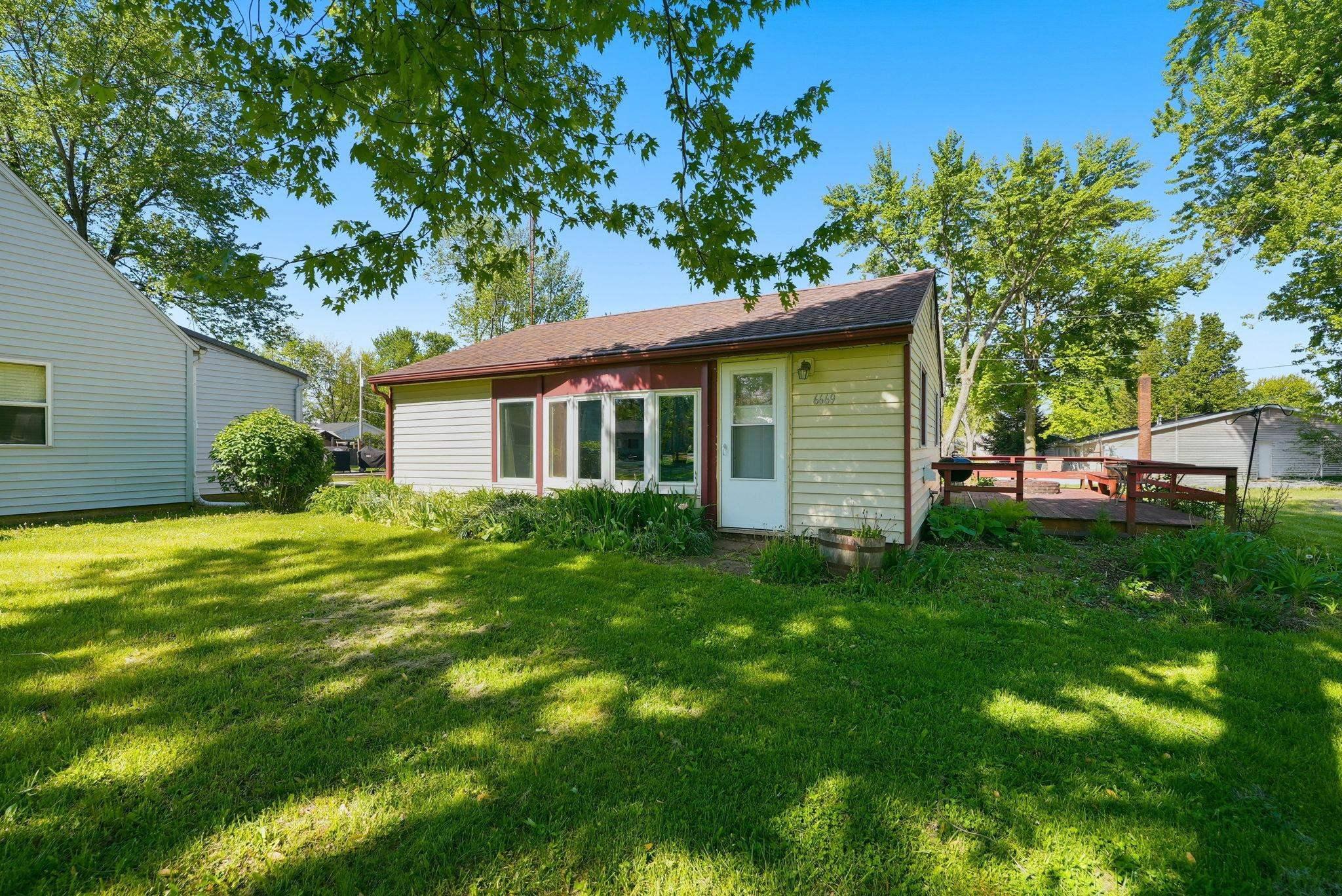 Image 2: Rear elevation featuring light-colored siding, a contrasting red trim, and a prominent sunroom with multiple windows, Back Of Structure Image 2: Rear elevation featuring light-colored siding, a contrasting red trim, and a prominent sunroom with multiple windows, Back Of Structure